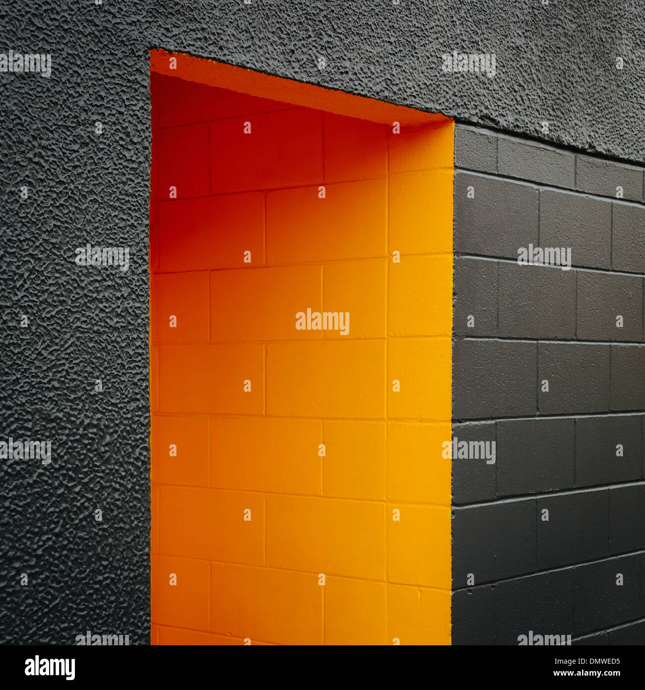 Une porte peinte en orange évidement un bloc gris mur de béton. Banque D'Images