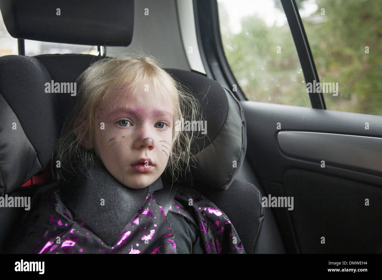 Une jeune fille dans un siège de voiture en costume d'Halloween. Banque D'Images