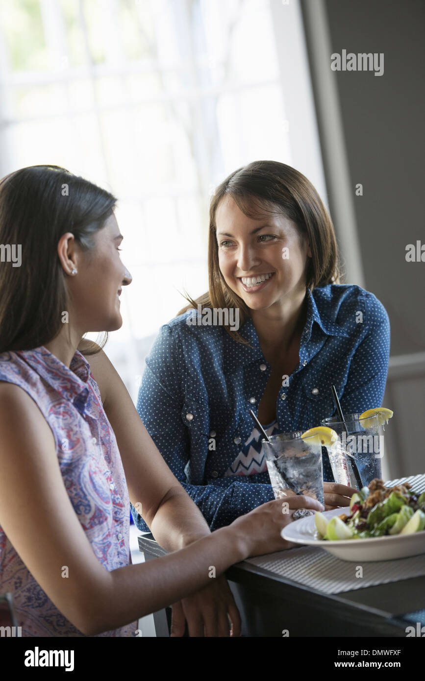 Deux femmes assises à une table de café ayant un repas. Banque D'Images