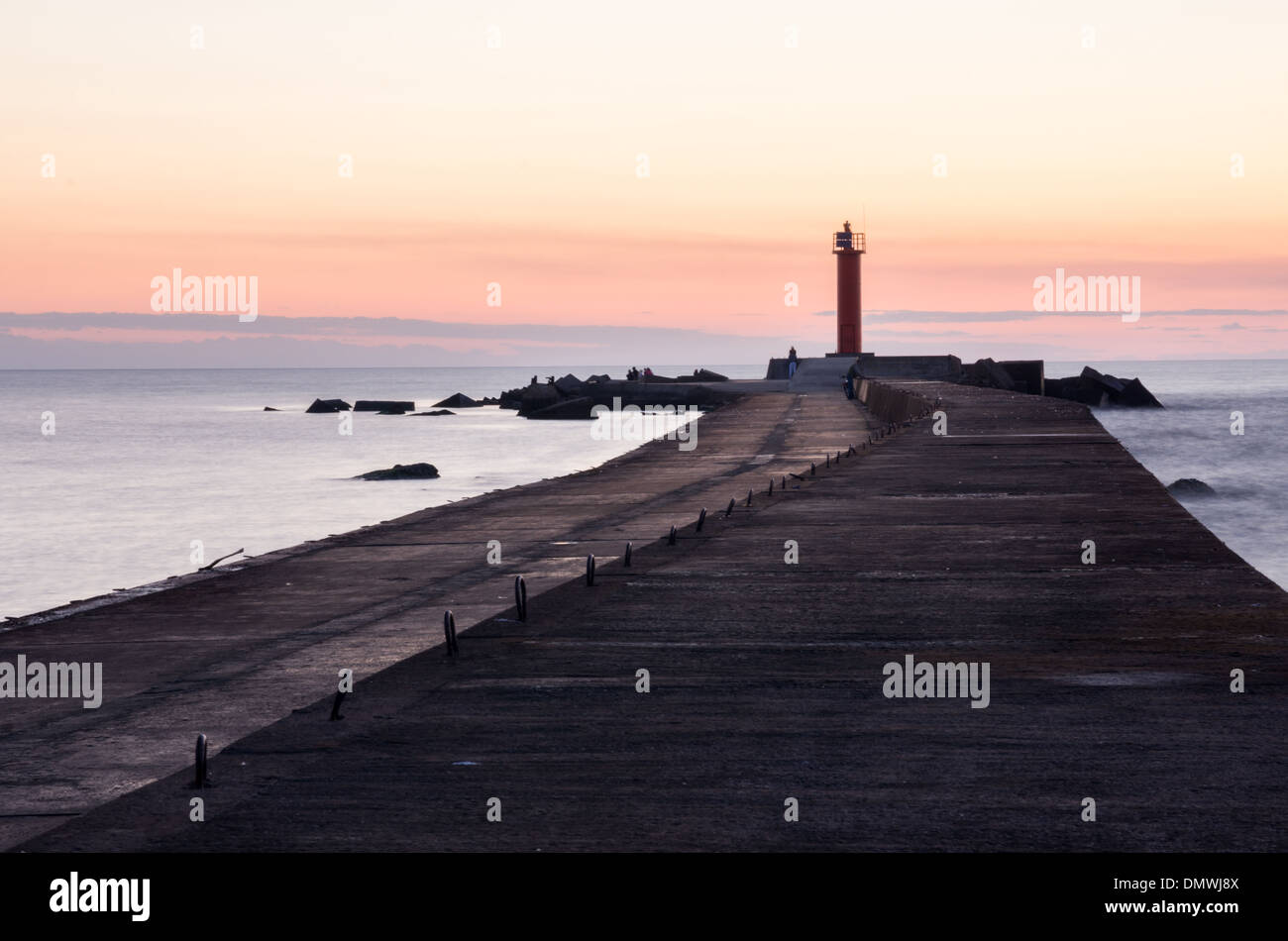 Une scène colorée après le coucher du soleil au bord de la mer. daugava se jette dans la baie de Riga de la mer Baltique. mole de béton et le phare. Banque D'Images