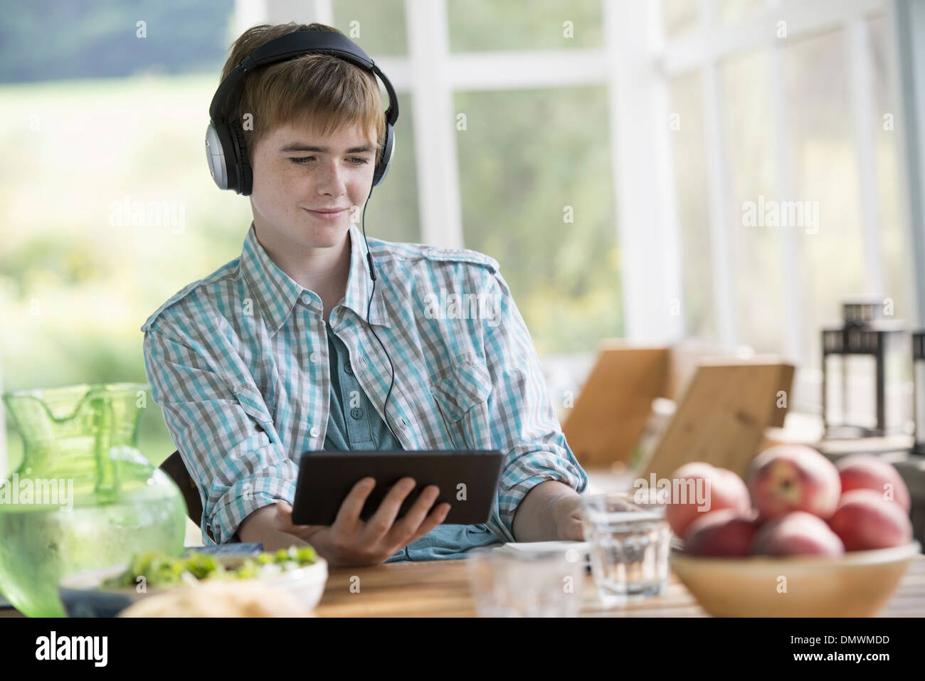 Un jeune garçon à l'écoute de la musique et à l'aide d'une tablette numérique. Banque D'Images