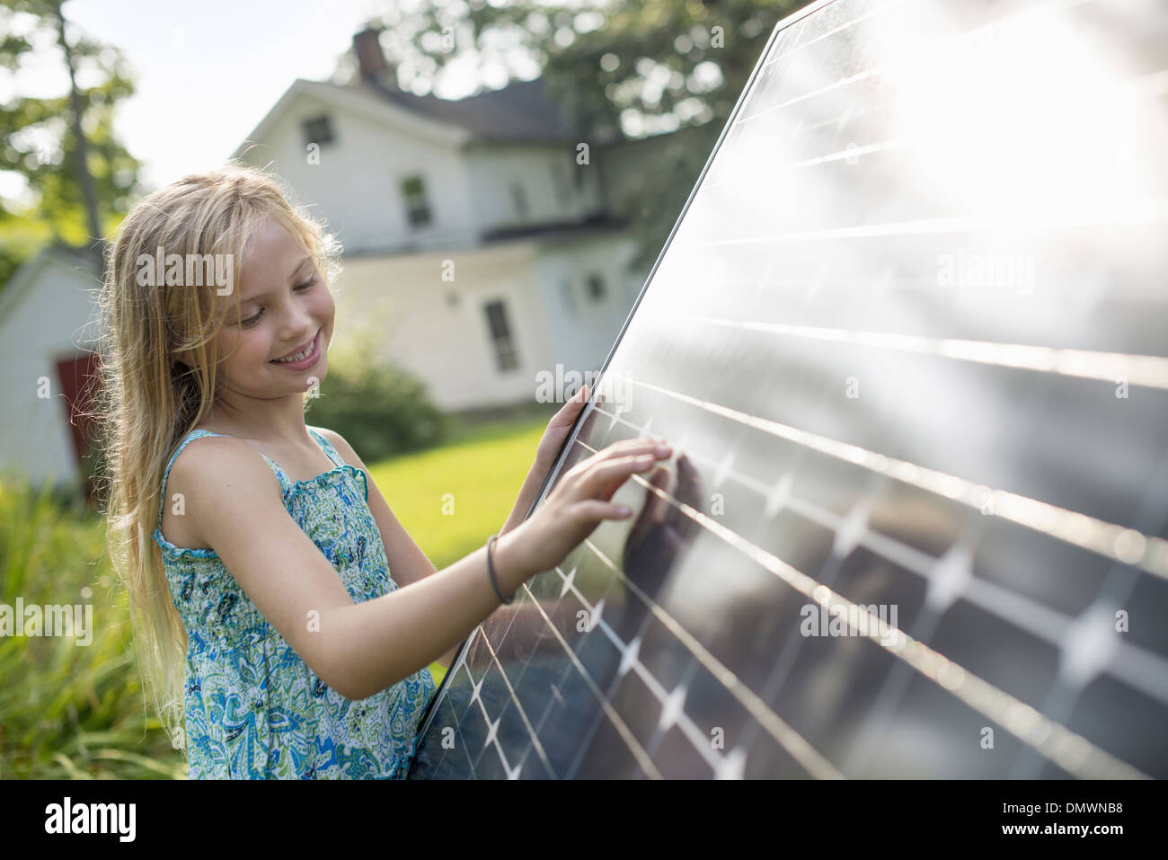 Une jeune fille à côté d'un grand panneau solaire jardin dans une ferme. Banque D'Images