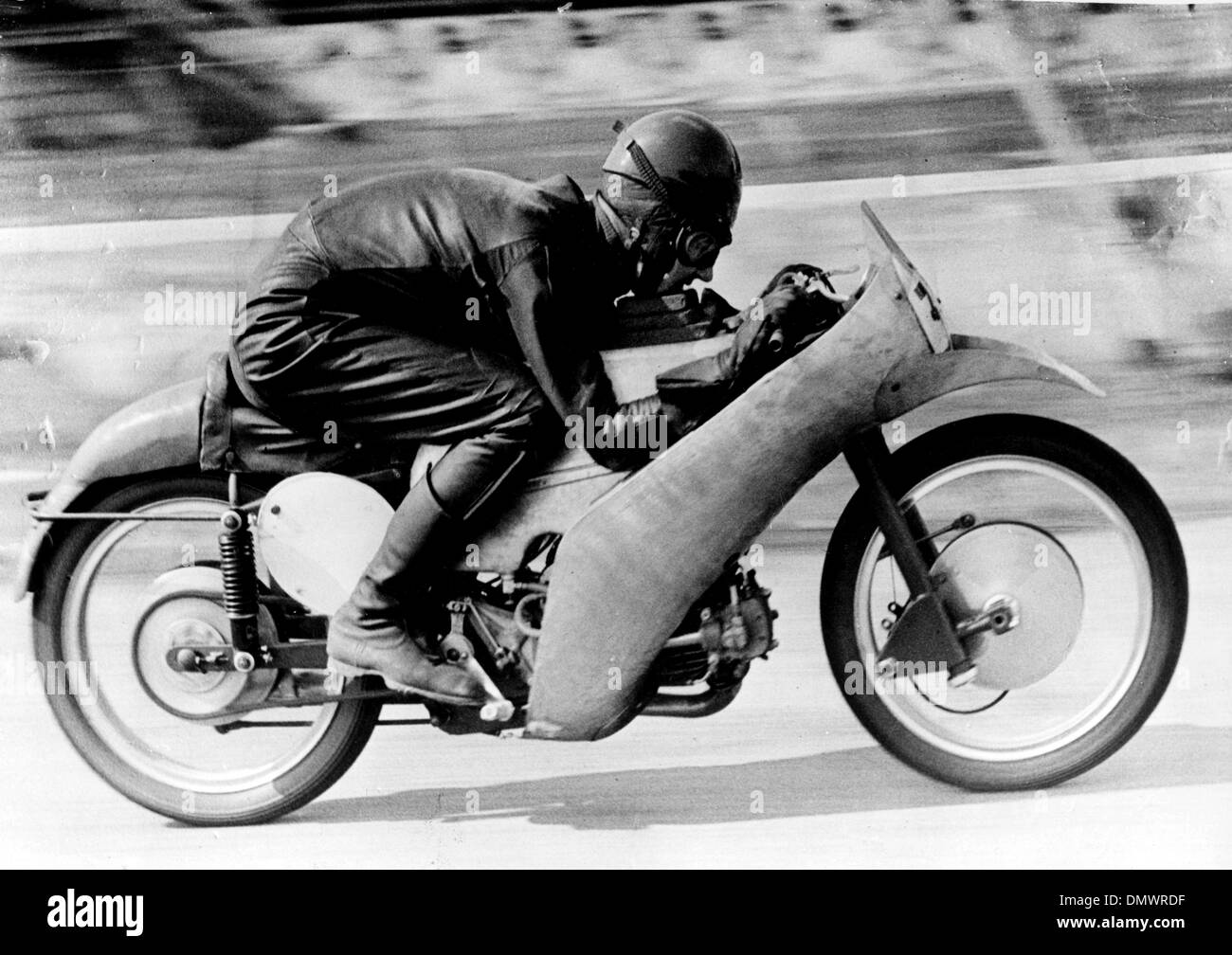 19 mars 1954 - Monza, Italie - Les Britanniques FERGUS ANDERSON motocycliste, a été parmi les nombreux coureurs qui participent à l'événement sur le circuit de Monza en Italie récemment. La réunion a été également assisté par le glamour Marta Toren actrice suédoise. Sur la photo : Fergus Anderson utilise chin pads comme il s'accroupit sur le réservoir de la 350 cc. Moto Guzzi machine sur laquelle il s'est rendu à 200 km Banque D'Images