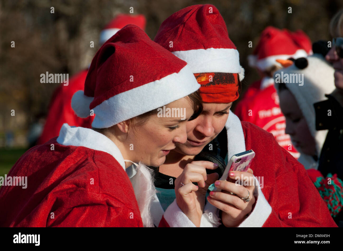 Santa Run- gens portant des costumes Santa au profit de différents organismes de bienfaisance, organisé par "oitforcharity».Deux coureurs d'oeil à un téléphone. Banque D'Images