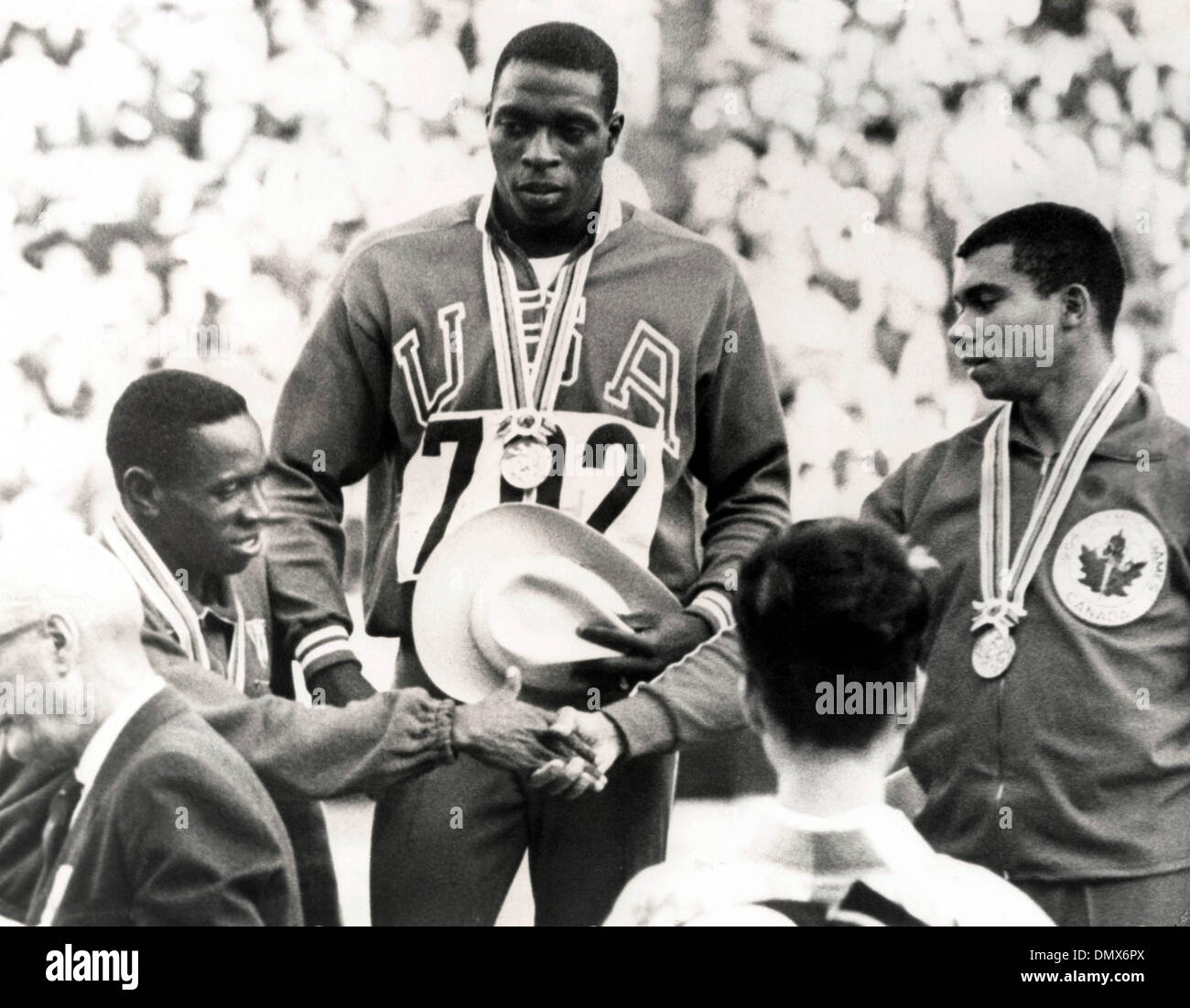 16 octobre 1964 - Tokyo, Japon - coureur américain Bob Hayes, né Robert Lee Hayes, sur la tribune portant sa médaille d'or pendant qu'il observe le peuple cubain Enrique Figuerola (L) qui a obtenu la deuxième place féliciter le Harry Jerome canadien qui était troisième après la finale du 100 mètres à Tokyo en 1964. (Crédit Image : © Keystone Photos/ZUMAPRESS.com) Banque D'Images