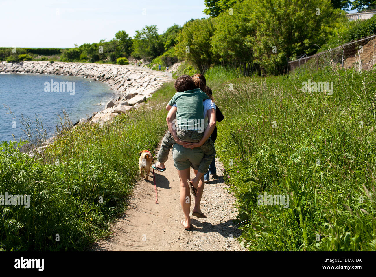 Une mère donne un fils un piggyback ride le long d'une section de Cliff Walk, une attraction populaire et marcher à Newport Rhode Island Banque D'Images