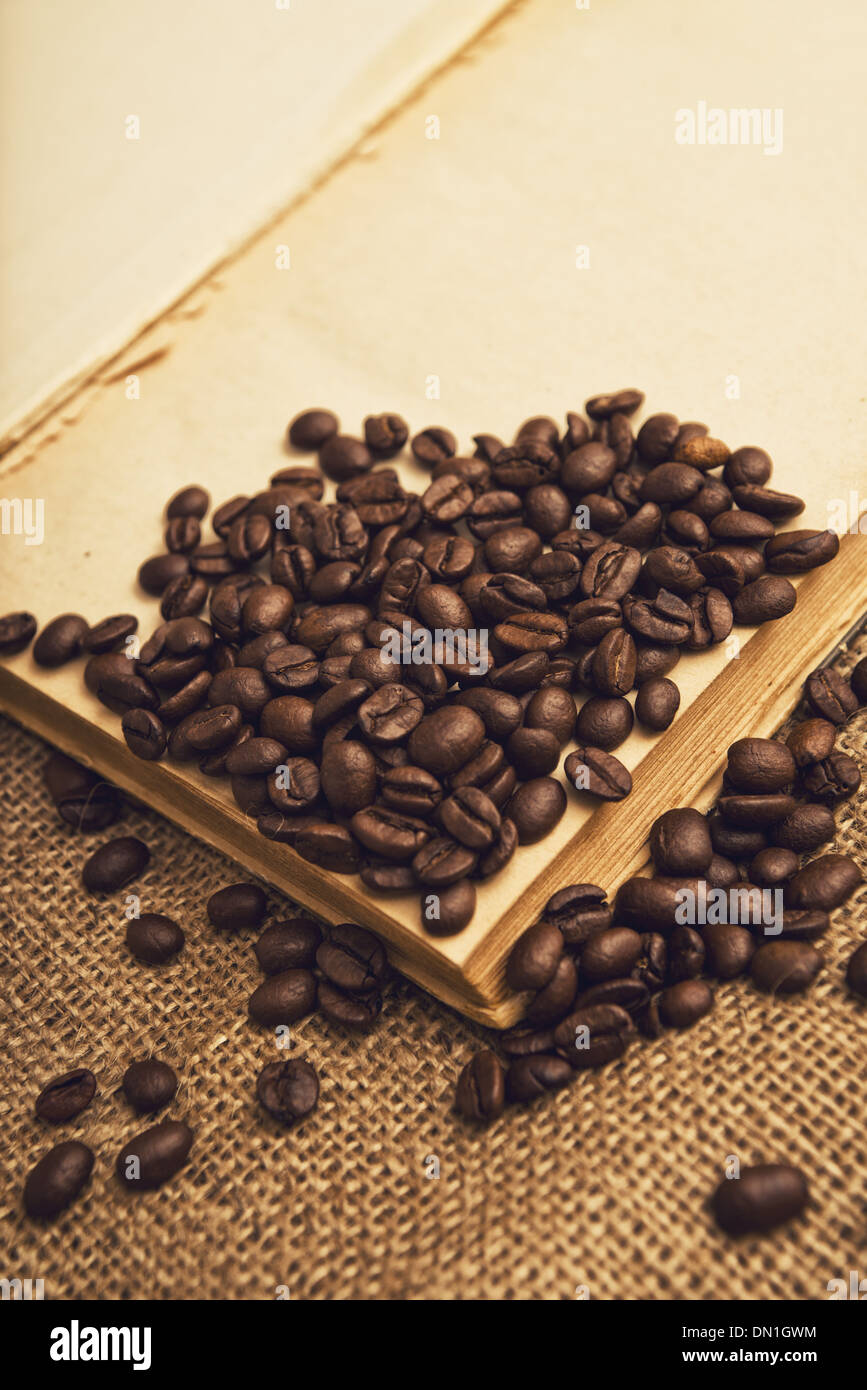 Les grains de café et livre ouvert sur la texture de toile de jute. Banque D'Images