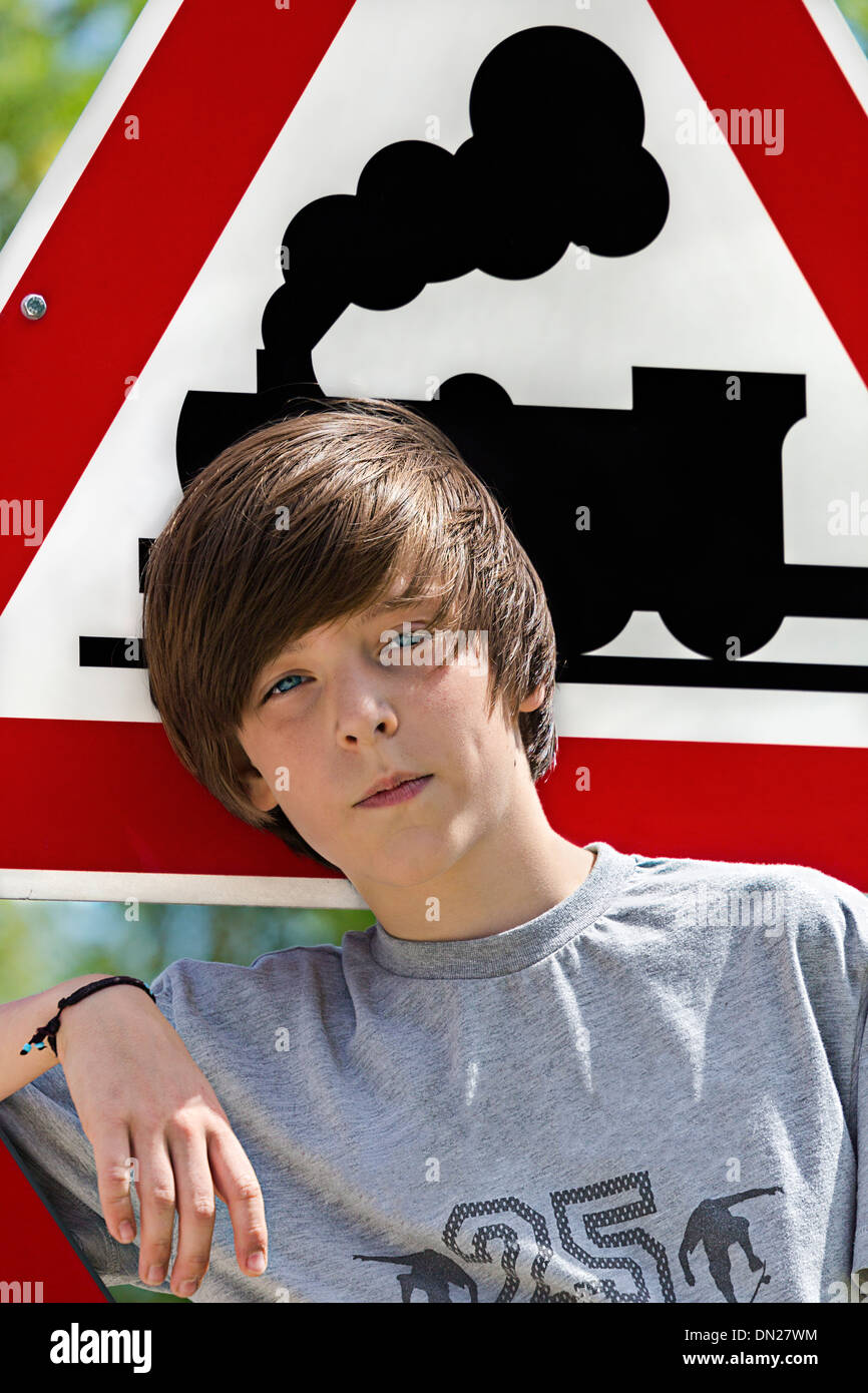Portrait d'un garçon en face d'un panneau de circulation de locomotives. Banque D'Images