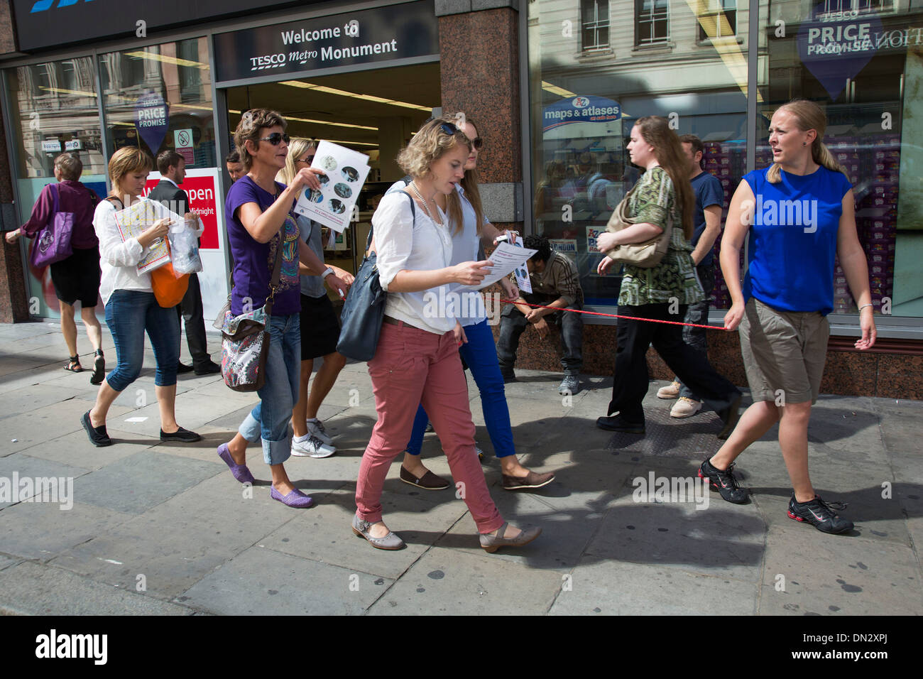 Les touristes de prendre part à une chasse au trésor à pied le long d'ensemble tenant une corde pour se tenir ensemble en tant que groupe. Londres, Royaume-Uni. Banque D'Images