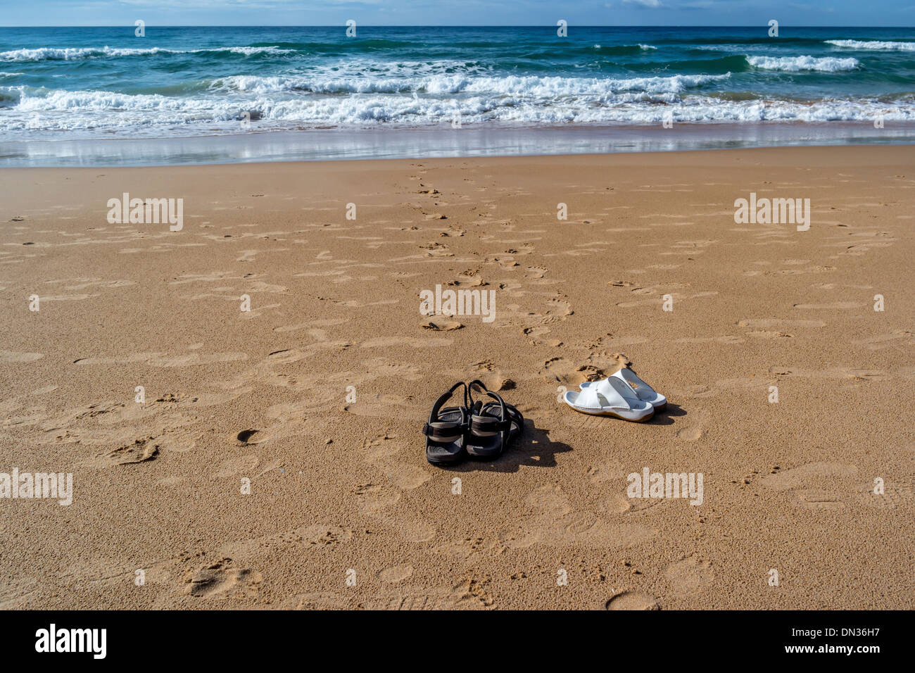 Sandales à gauche sur la plage avec des traces d'entrer dans la mer Banque D'Images