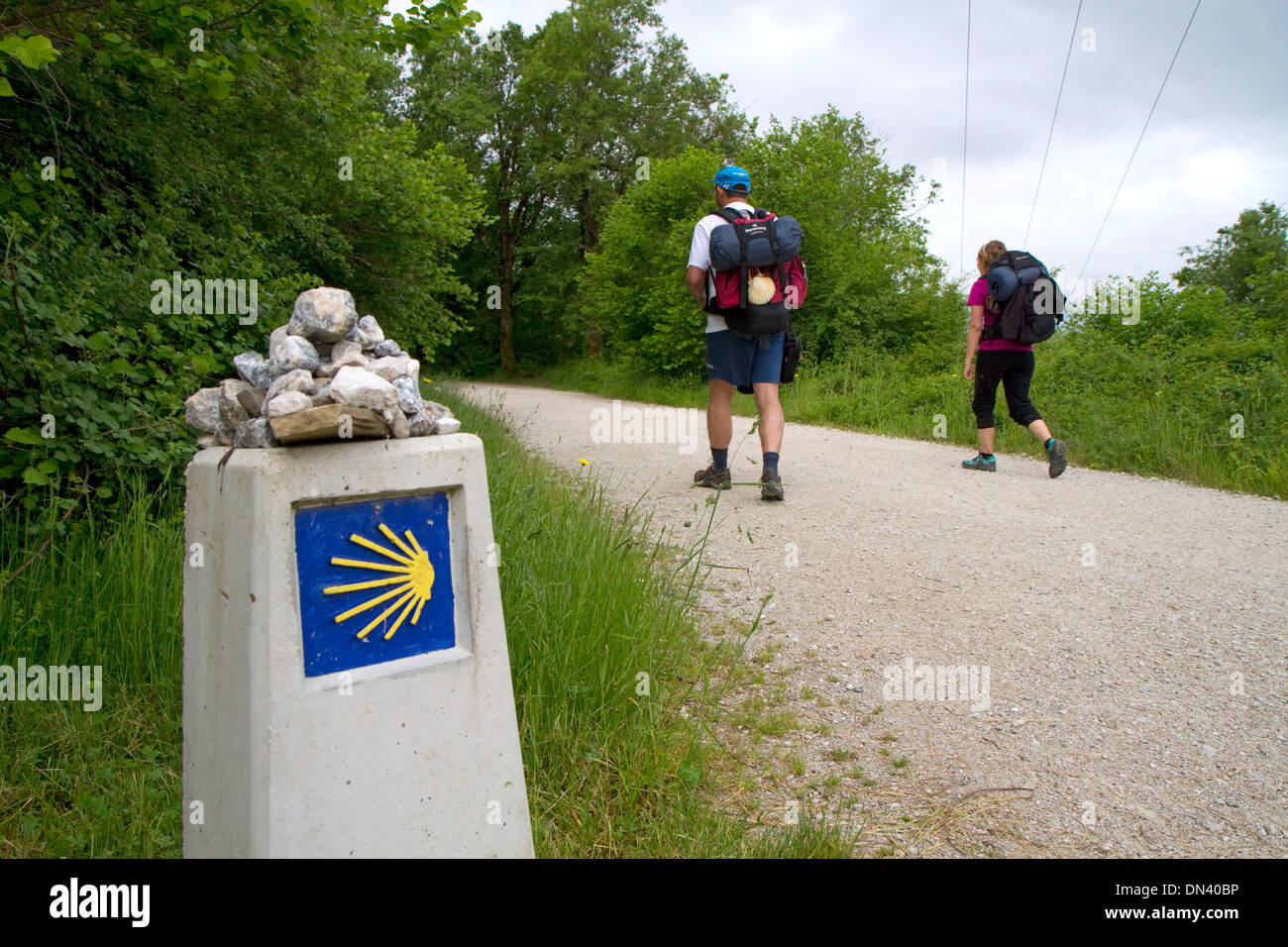 Les Pèlerins à pied près d'un marqueur le long du Camino de Santiago, le Chemin de Saint-Jacques de Compostelle, Navarra, Espagne. Banque D'Images