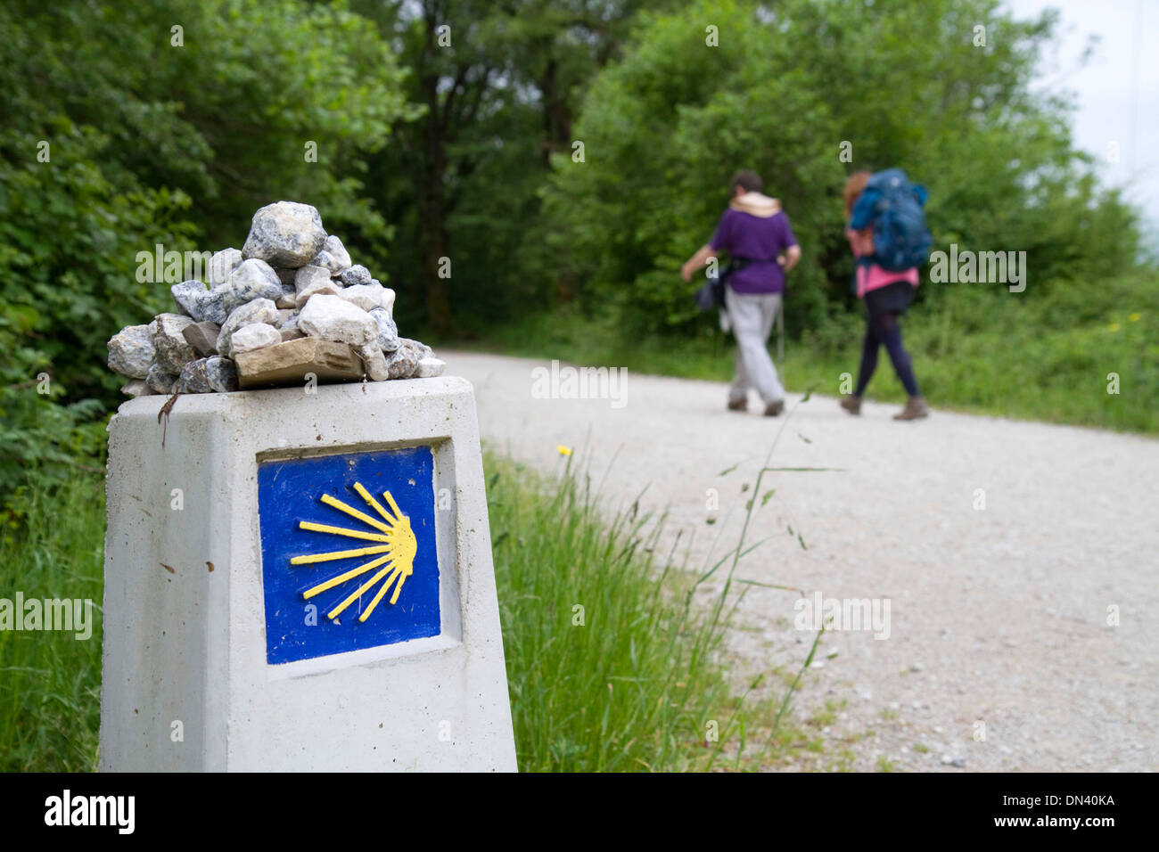 Les Pèlerins à pied près d'un marqueur le long du Camino de Santiago, le Chemin de Saint-Jacques de Compostelle, Navarra, Espagne. Banque D'Images