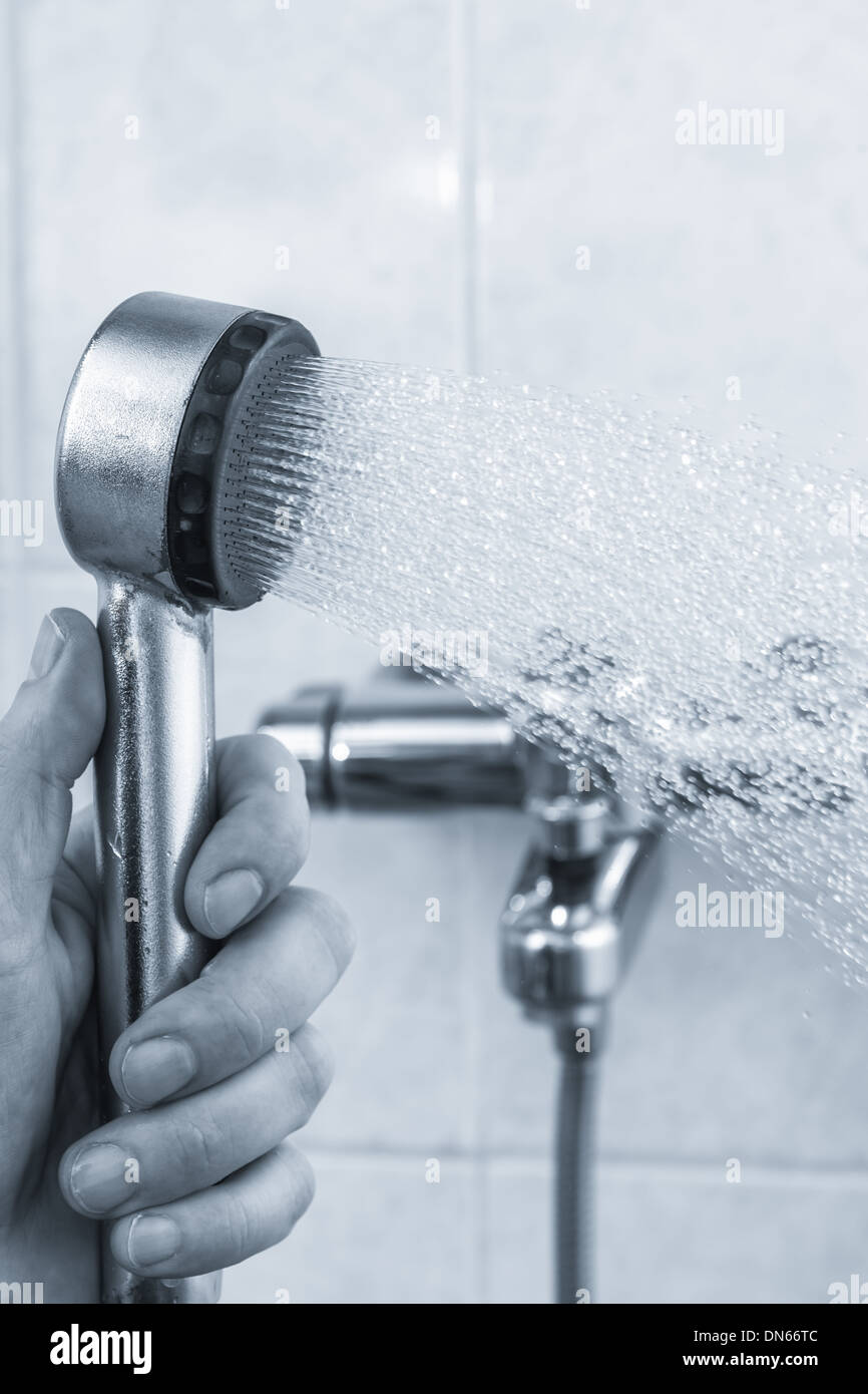 Un homme tient ouverte de douche dans la salle de bains, teinté en noir et blanc, format vertical Banque D'Images