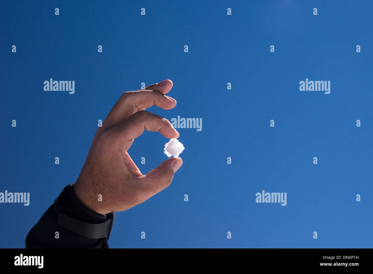 L'homme est titulaire d'un nouveau cristal de sel dans sa main contre le ciel bleu, Salar de Uyuni, Bolivie, Amérique du Sud Banque D'Images