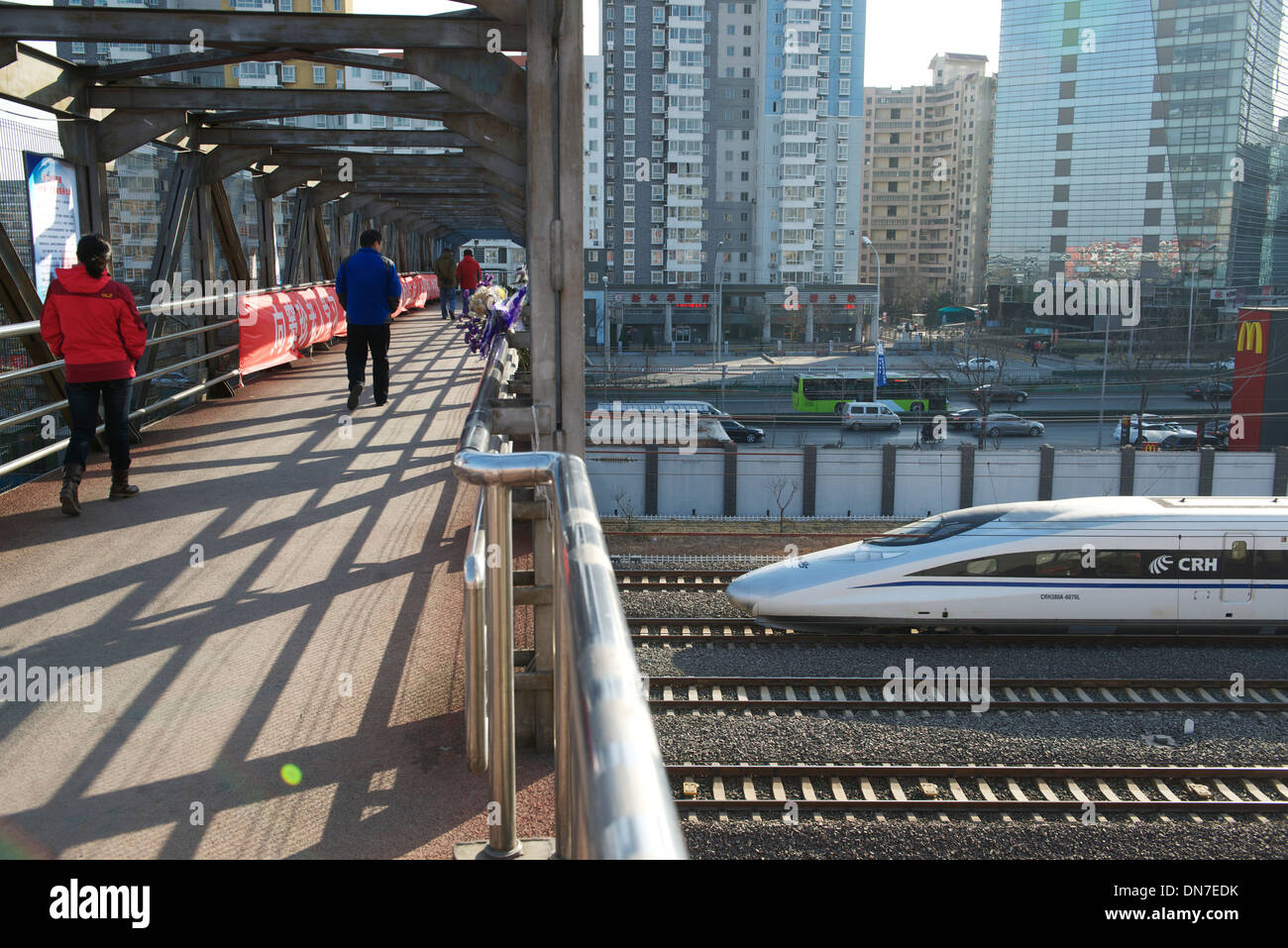 On marche sur une passerelle alors qu'un train à grande vitesse va passer en gare sud de Beijing, à Beijing, en Chine. 15-Déc-2013 Banque D'Images