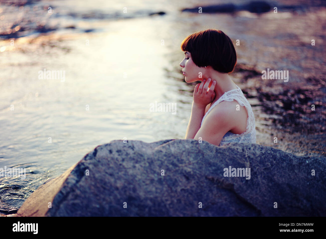 Jeune femme est assise sur un creek Banque D'Images