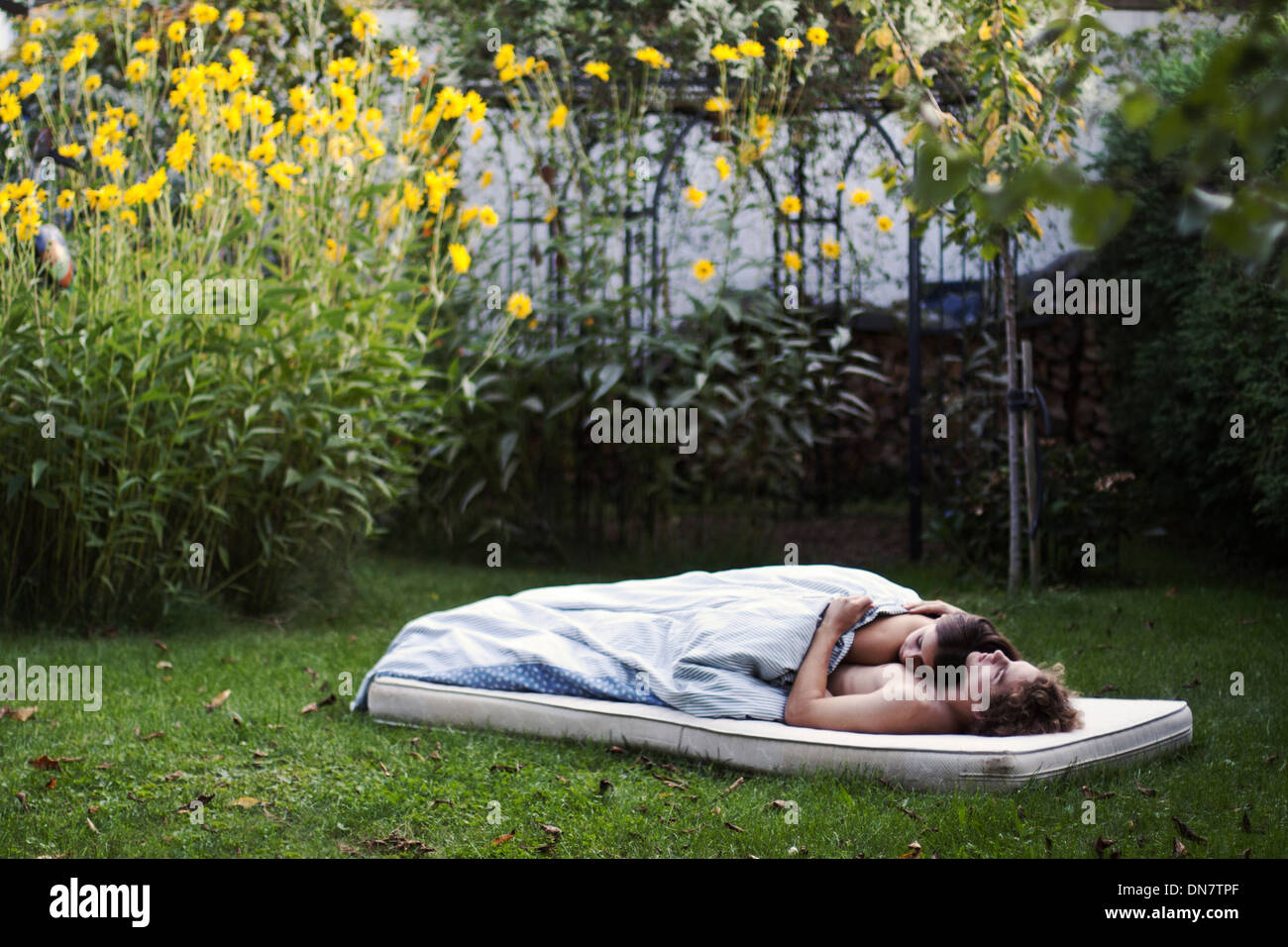 Couple aimant se trouve endormi sur un matelas dans le jardin Banque D'Images