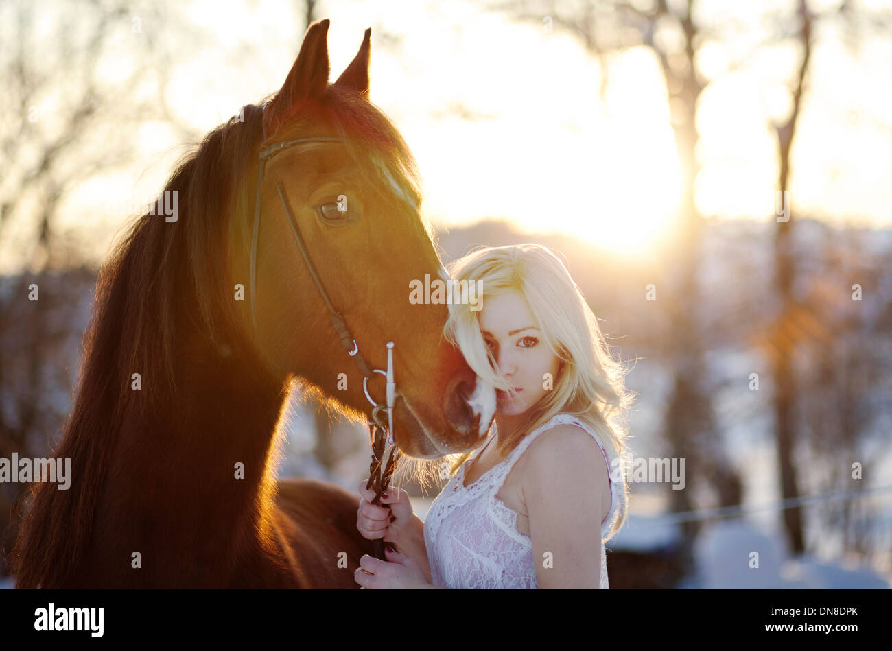Jeune femme en robe blanche à cheval en hiver Banque D'Images