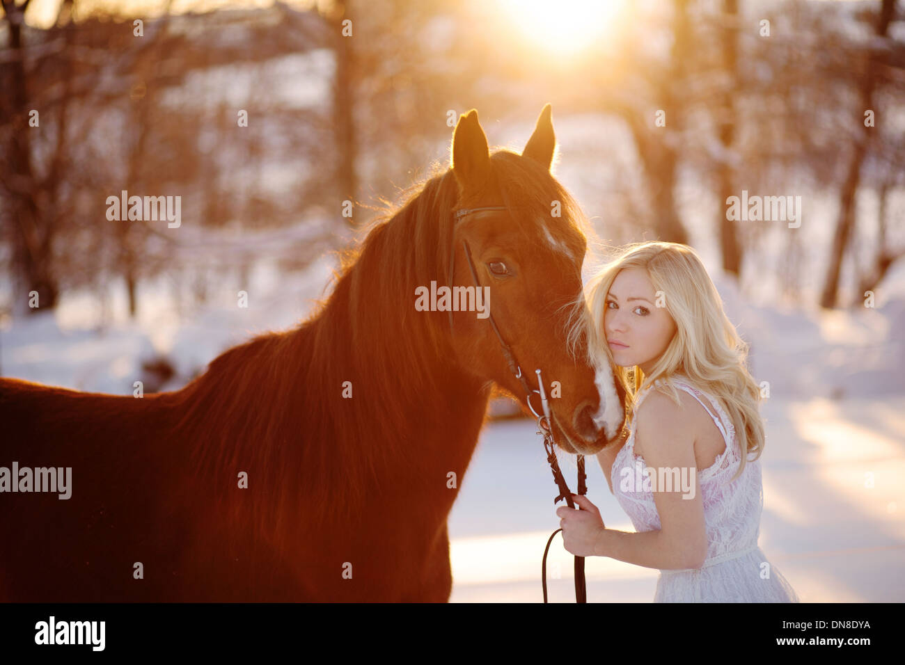 Jeune femme en robe blanche à cheval en hiver Banque D'Images