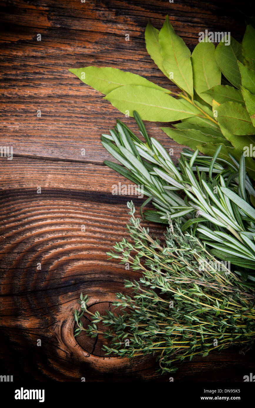De thym, romarin et laurier les feuilles de laurier liés sur une planche en bois Banque D'Images