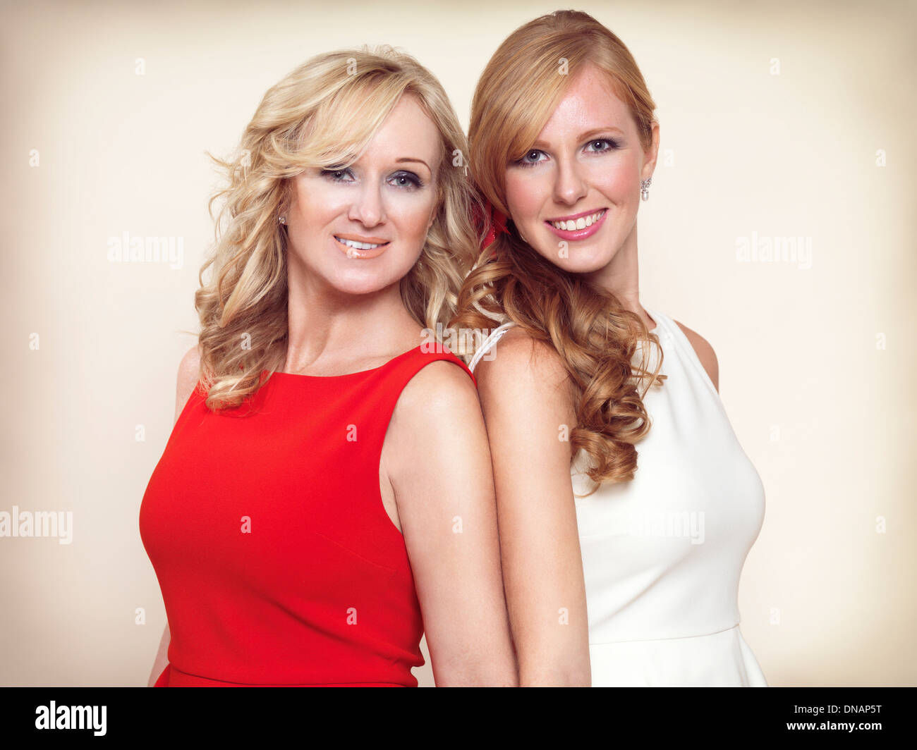 Portrait de deux sœurs souriant aux cheveux blonds se tenant ensemble isolé sur fond beige Banque D'Images