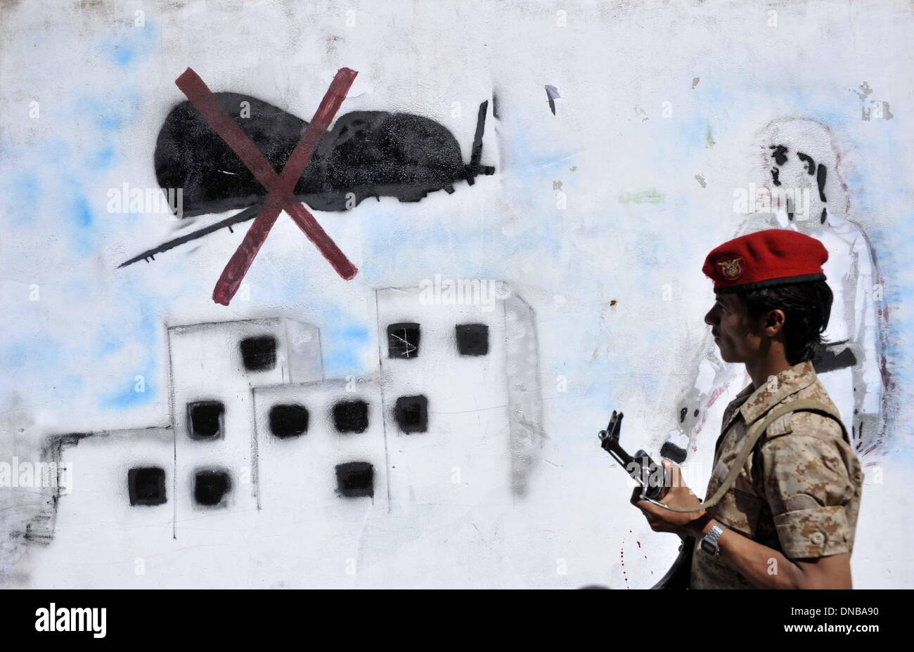 Sanaa, Yémen. 21e Mars 2014. Un soldat yéménite examine les graffiti de drone américain sur un mur peint en grève pour protester contre les frappes de drones, à Sanaa, Yémen, le 21 décembre 2013. Le parlement yéménite a approuvé une loi interdisant le dimanche sur des drones américains dans le pays après des dizaines de civils ont été tués par les avions sans pilote, l'agence de presse officielle Saba. La décision a été prise après les États-Unis frappé par erreur un mariage drone transmettre le jeudi dans le sud-est du Yémen, province d'al-Bayda, tuant jusqu'à 17 civils yéménites et blessant environ 21 autres. Source : Xinhua/Alamy Live News Banque D'Images