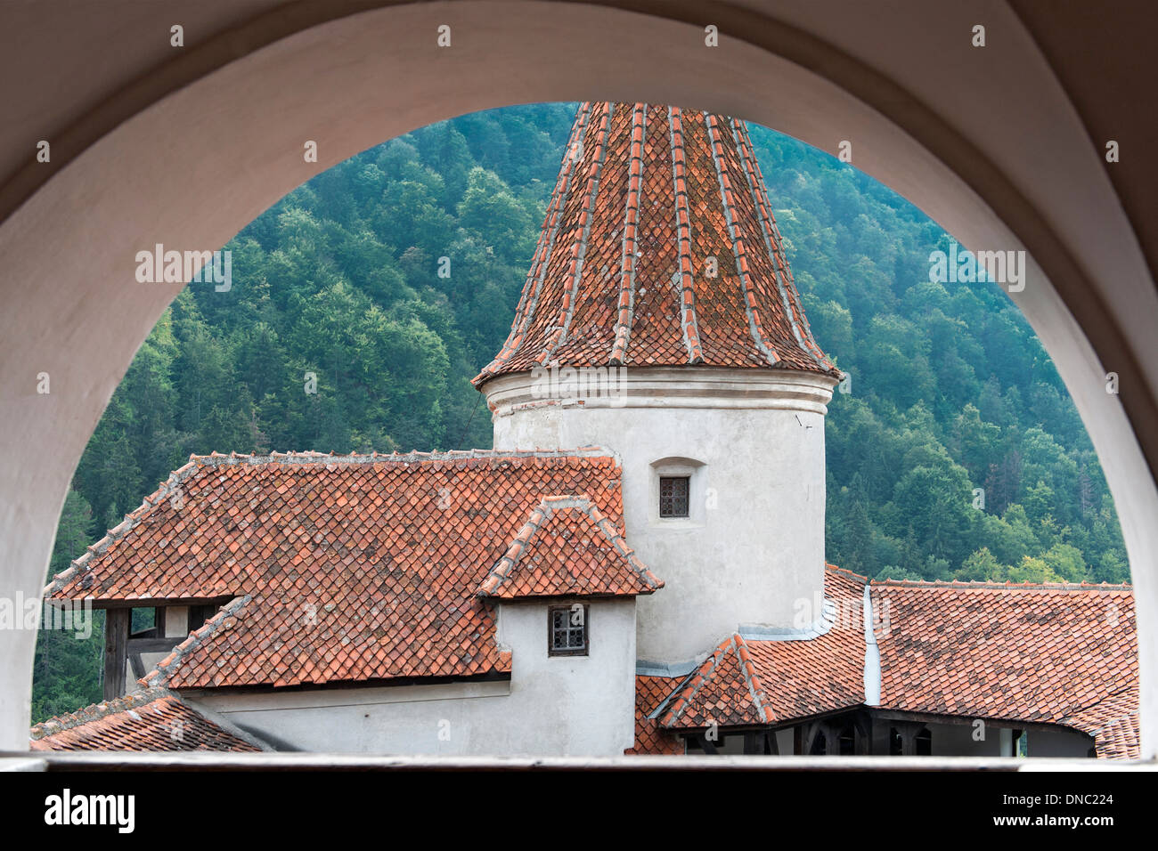 Vue à travers une arcade des toits et la tour du château de Bran dans la région de Transylvanie du centre de la Roumanie. Banque D'Images