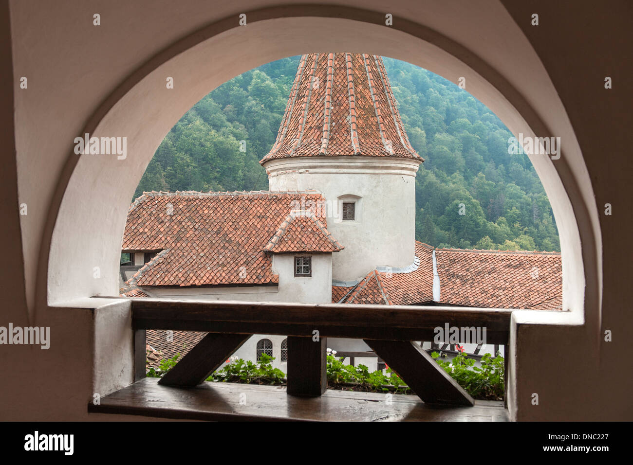 Vue à travers une arcade des toits et la tour du château de Bran dans la région de Transylvanie du centre de la Roumanie. Banque D'Images