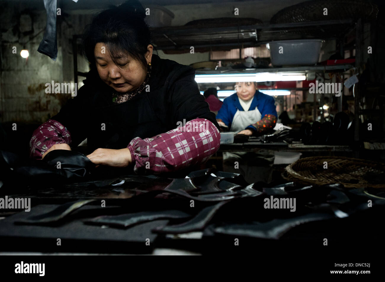 Chongqing, Chine - 31 décembre 2010 : une femme travaille sur des bottes dans une petite usine de fabrication de la production de chaussures. Banque D'Images