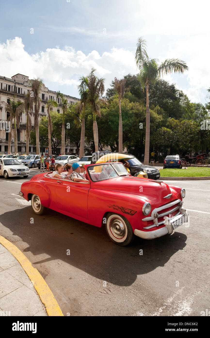 Famille dans une vieille voiture américaine rouge travaillant comme un taxi ; le Parque Central, La Havane, Cuba Caraïbes, Amérique Latine Banque D'Images