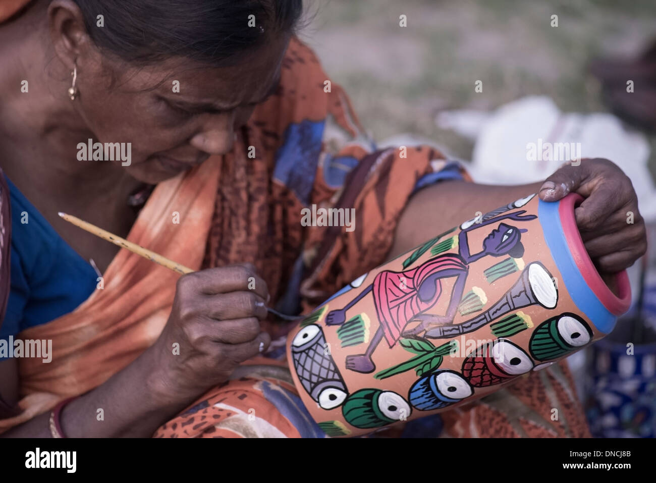 Les femmes sud-asiatiques du peintre défilement road side Stall, expose ses peintures, défilement sur un pot en terre,une dame tribal. Banque D'Images