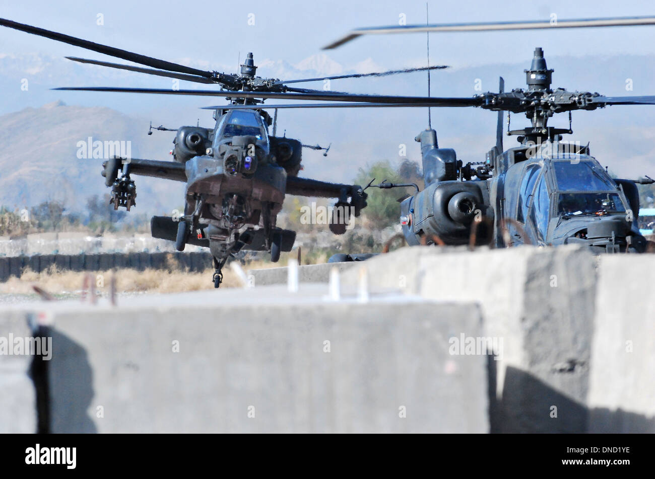 AH-64 Apache de l'armée américaine d'hélicoptères d'attaque dans l'approche de l'armement de l'avant et d'une station d'antenne armés de mission d'escorte, 13 décembre 2013 à l'Aérodrome de Jalalabad, en Afghanistan. Banque D'Images
