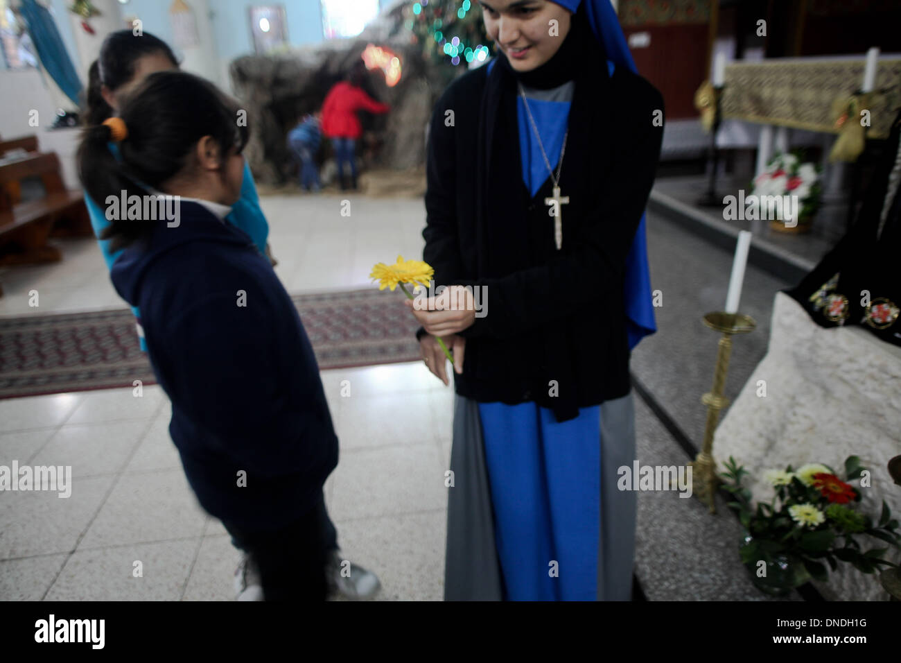 Gaza, Territoires palestiniens. Dec 23, 2013. Une religieuse brésilienne donne une fleur à une fille chrétienne palestinienne à l'Église catholique dans la ville de Gaza pendant les préparatifs pour célébrer le jour de Noël le 23 décembre 2013.Photo : Ahmed Deeb/NurPhoto Crédit : Ahmed Deeb/NurPhoto ZUMAPRESS.com/Alamy/Live News Banque D'Images