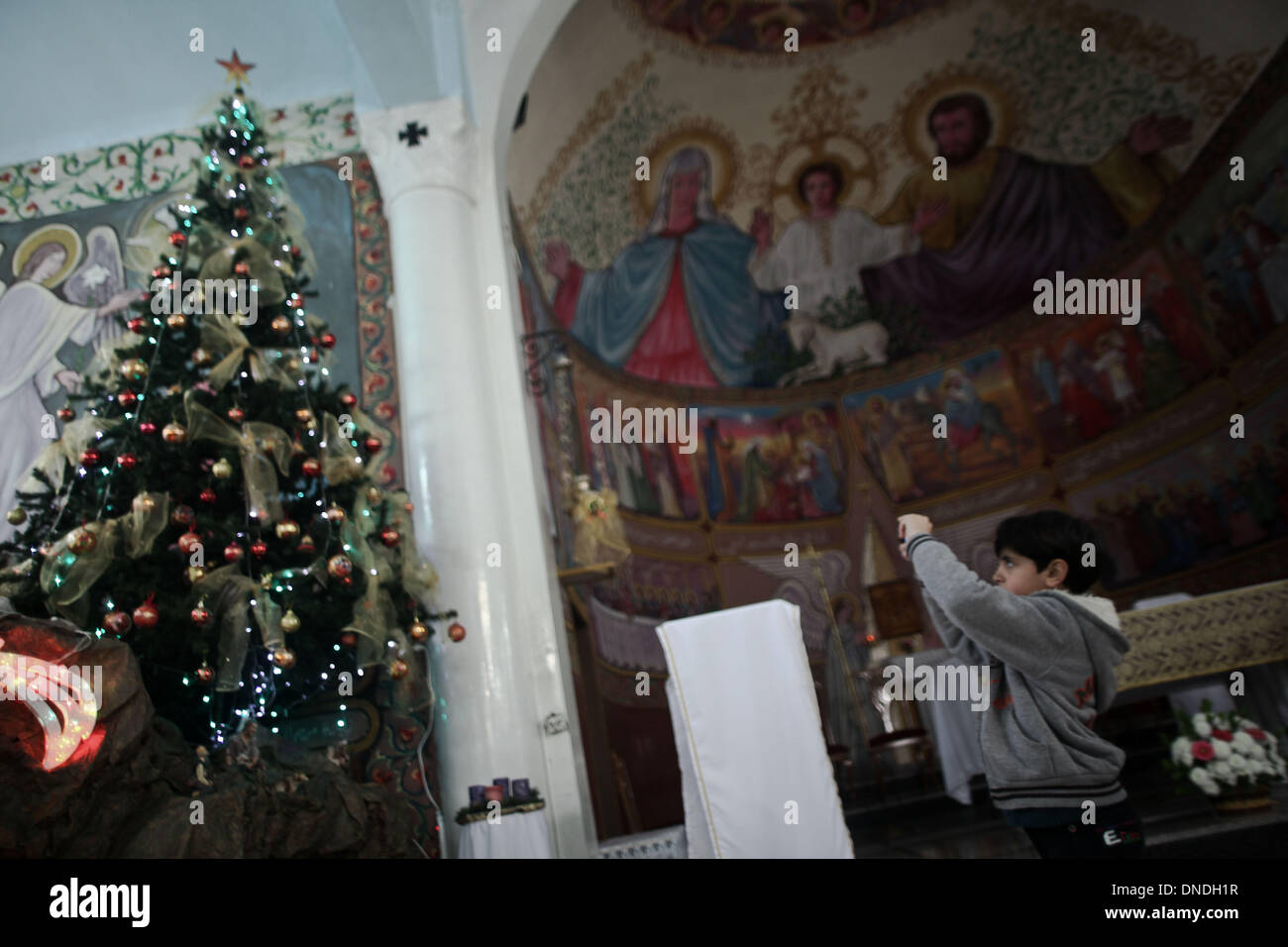 Gaza, Territoires palestiniens. Dec 23, 2013. Un chrétien palestinien garçon prend photo de son portable à l'arbre de Noël à l'Église catholique dans la ville de Gaza pendant les préparatifs pour célébrer le jour de Noël le 23 décembre 2013.Photo : Ahmed Deeb/NurPhoto Crédit : Ahmed Deeb/NurPhoto ZUMAPRESS.com/Alamy/Live News Banque D'Images