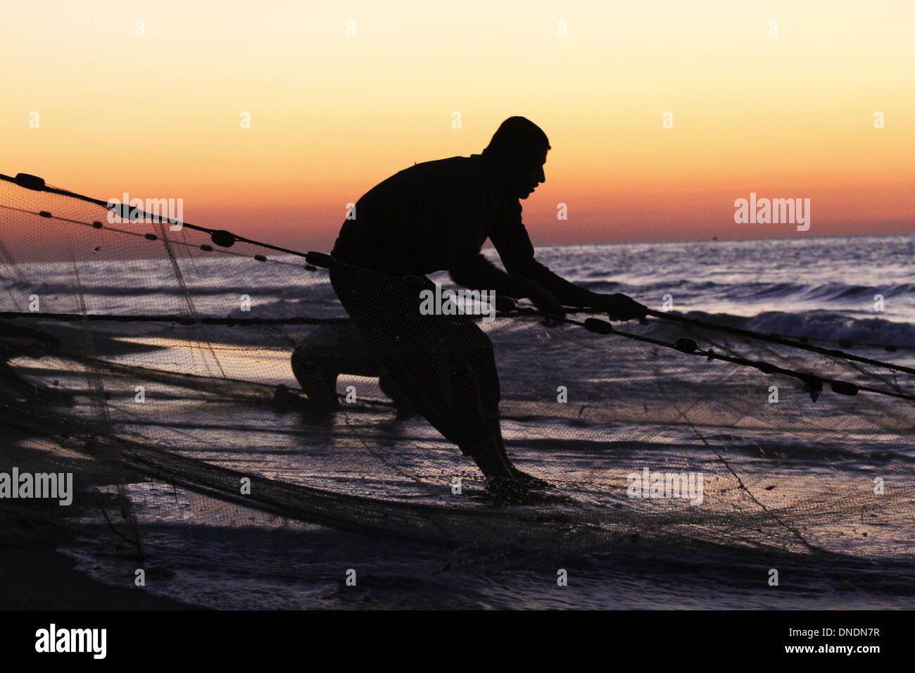 Gaza, Territoires palestiniens. Dec 23, 2013. Un pêcheur palestinien tirer un bénéfice net de la mer Méditerranée au coucher du soleil dans la ville de Gaza le 23 décembre 2013. Photo : Sameh Rahmi/NurPhoto Crédit : Sameh Rahmi/NurPhoto ZUMAPRESS.com/Alamy/Live News Banque D'Images