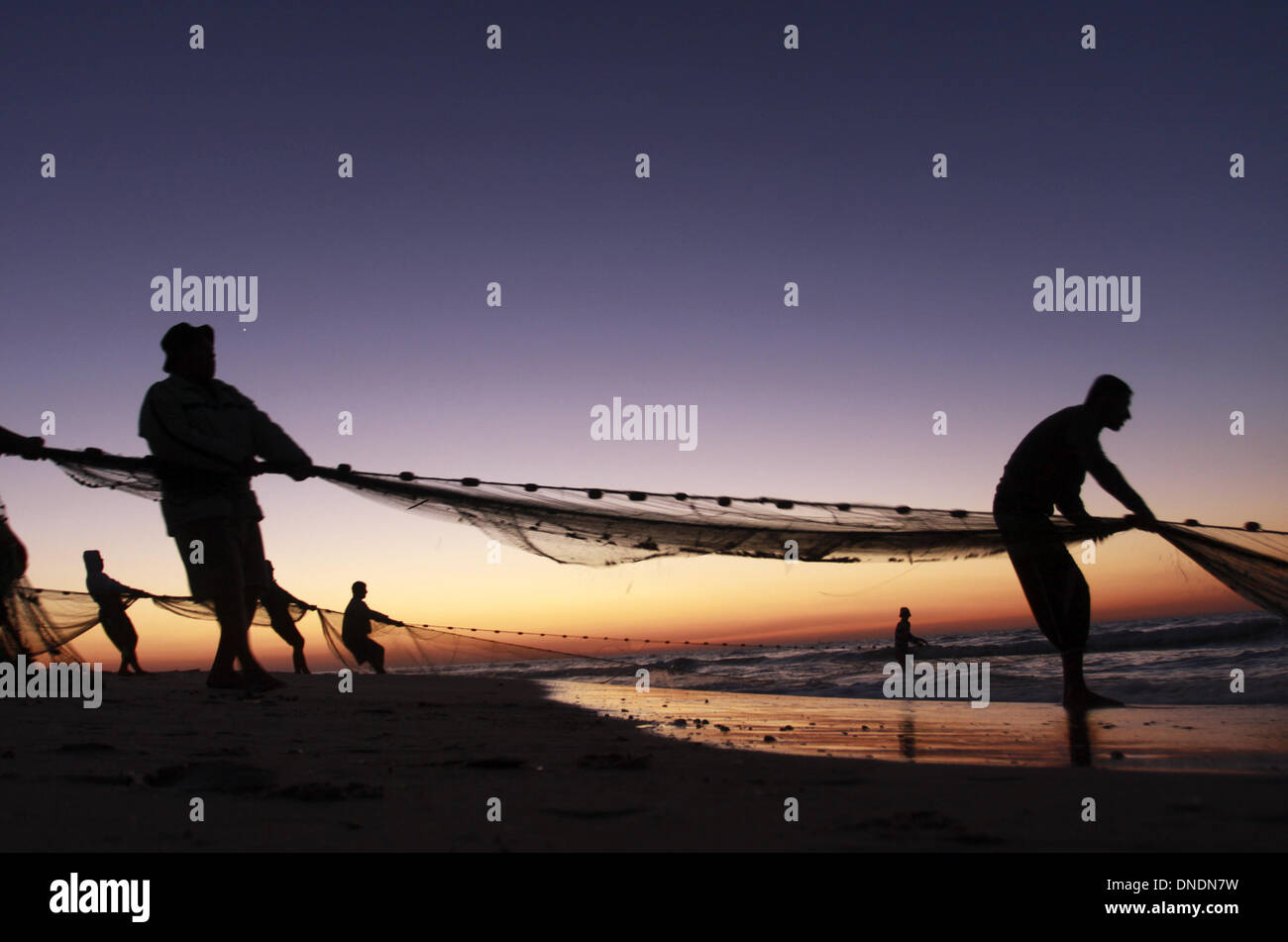 Gaza, Territoires palestiniens. Dec 23, 2013. Les pêcheurs palestiniens tirer leurs filets de la mer Méditerranée au coucher du soleil dans la ville de Gaza le 23 décembre 2013.Photo : Sameh Rahmi/NurPhoto Crédit : Sameh Rahmi/NurPhoto ZUMAPRESS.com/Alamy/Live News Banque D'Images