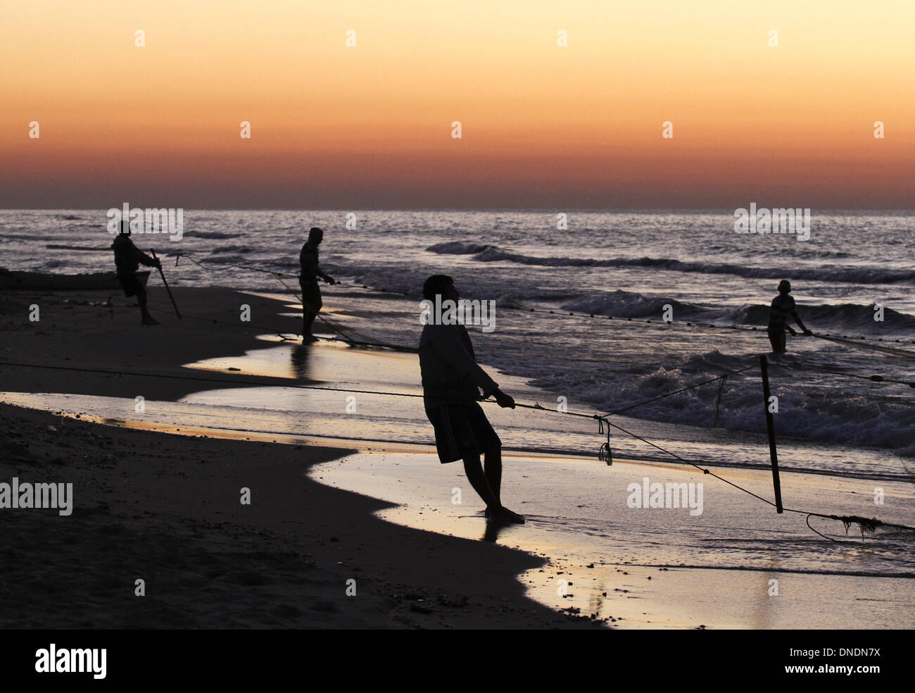 Gaza, Territoires palestiniens. Dec 23, 2013. Les pêcheurs palestiniens tirer leurs filets de la mer Méditerranée au coucher du soleil dans la ville de Gaza le 23 décembre 2013. Photo : Sameh Rahmi/NurPhoto Crédit : Sameh Rahmi/NurPhoto ZUMAPRESS.com/Alamy/Live News Banque D'Images