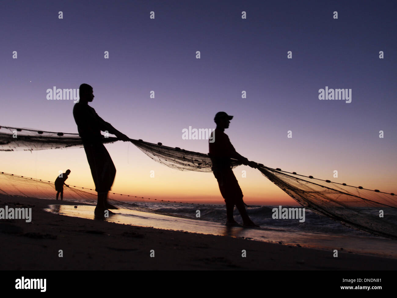 Gaza, Territoires palestiniens. Dec 23, 2013. Les pêcheurs palestiniens tirer leurs filets de la mer Méditerranée au coucher du soleil dans la ville de Gaza le 23 décembre 2013. Photo : Sameh Rahmi/NurPhoto Crédit : Sameh Rahmi/NurPhoto ZUMAPRESS.com/Alamy/Live News Banque D'Images