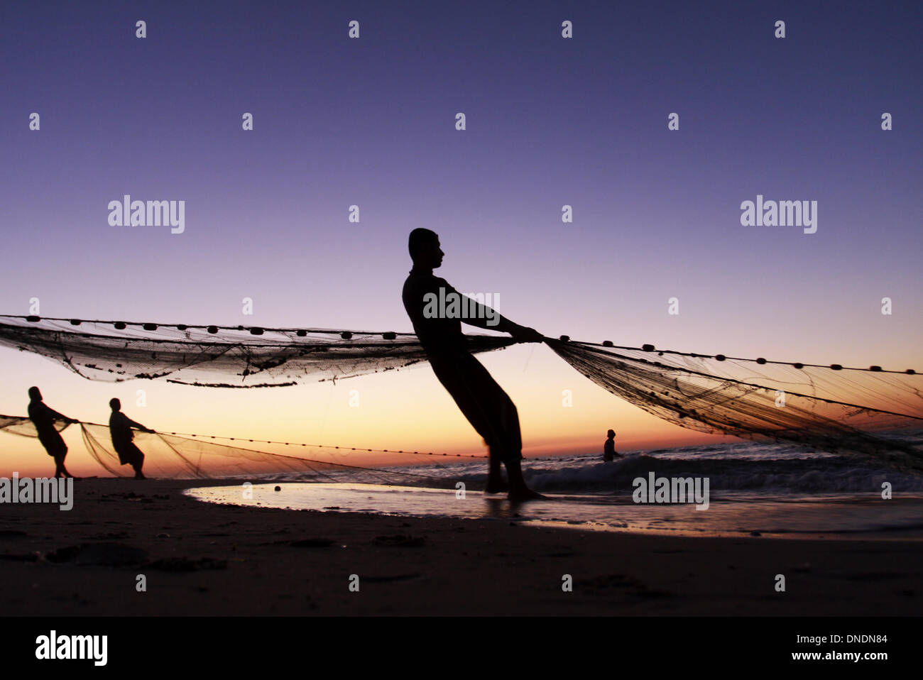Gaza, Territoires palestiniens. Dec 23, 2013. Les pêcheurs palestiniens tirer leurs filets de la mer Méditerranée au coucher du soleil dans la ville de Gaza le 23 décembre 2013.Photo : Sameh Rahmi/NurPhoto Crédit : Sameh Rahmi/NurPhoto ZUMAPRESS.com/Alamy/Live News Banque D'Images
