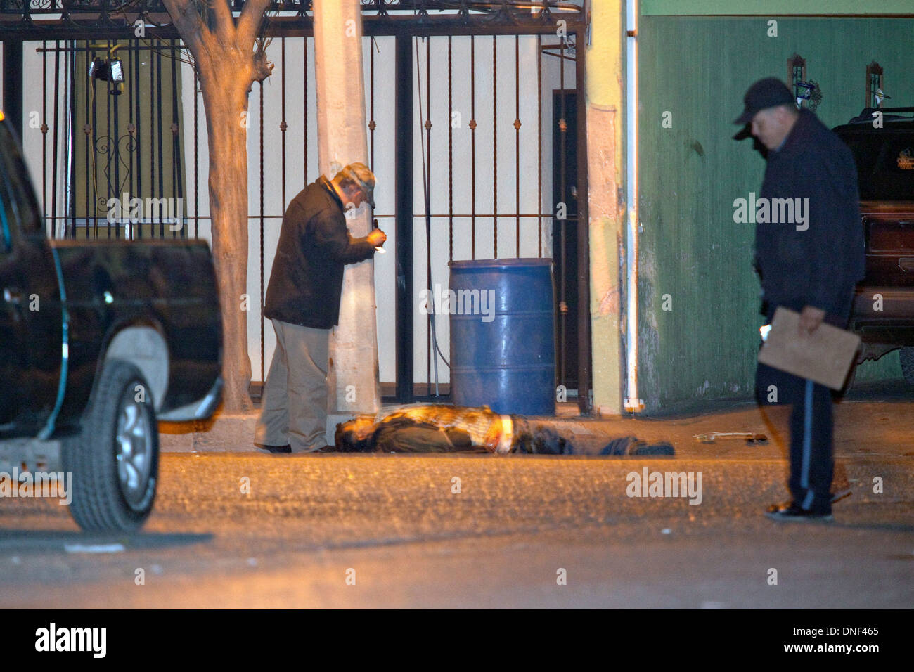 Un enquêteur de police examine le corps d'un homme tué par cartel assassin comme il est allé rendre visite à sa famille le 14 janvier 2009 à Juarez, au Mexique. Le tournage, liée à la drogue en cours à une guerre qui a déjà fait plus de 40 personnes depuis le début de l'année. Plus de 1600 personnes ont été tuées à Juarez en 2008, faisant de la ville la plus violente Juarez au Mexique. Banque D'Images