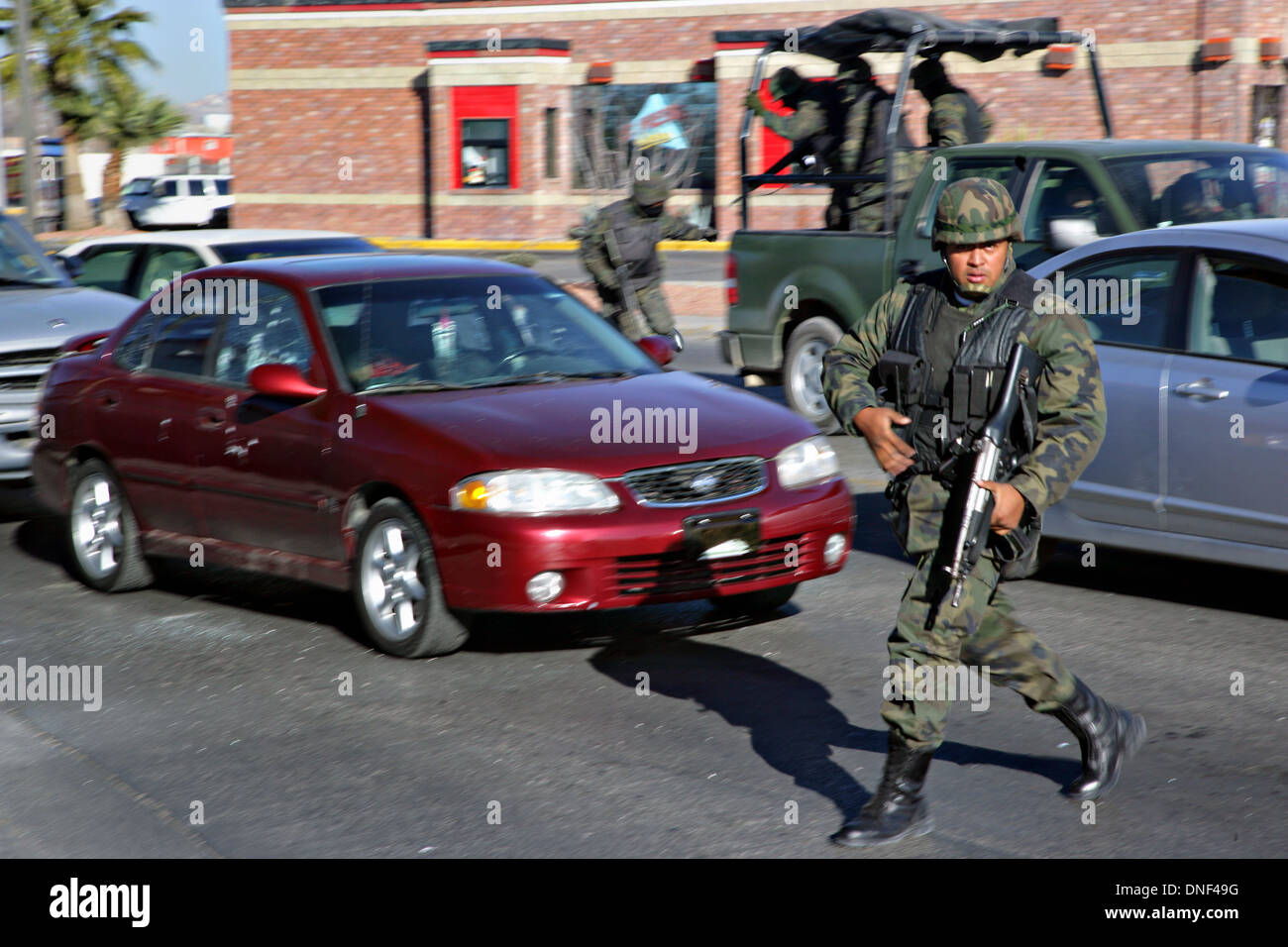 Les soldats de l'armée mexicaine répondre à un assassinat le long d'une route principale quelques instants après tireur armé abattu un ancien officier de police au cours de l'heure de pointe du matin que l'homme mort se trouve derrière le volant dans la voiture rouge le 16 janvier 2009 à Juarez, au Mexique. Le tournage, liée à la drogue en cours à une guerre qui a déjà fait plus de 40 personnes depuis le début de l'année. Plus de 1600 personnes ont été tuées à Juarez en 2008, faisant de la ville la plus violente Juarez au Mexique. Banque D'Images