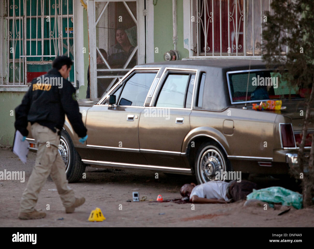 Les enquêteurs de police sur les lieux d'un médicament pousse dehors dans un taudis comme la famille Vue de derrière une porte moustiquaire 14 janvier 2009 à Juarez, au Mexique. Le tournage, liée à la drogue en cours à une guerre qui a déjà fait plus de 40 personnes depuis le début de l'année. Plus de 1600 personnes ont été tuées à Juarez en 2008, faisant de la ville la plus violente Juarez au Mexique. Banque D'Images