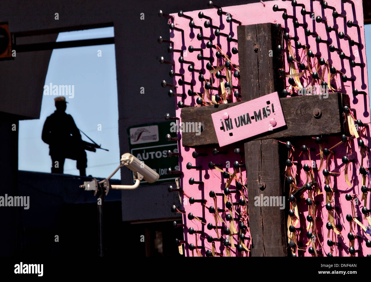 Un soldat se profile à l'Avenue Juarez border crossing aux etats unis que par un mémorial aux femmes tués dans la violence à Juarez, Mexique 14 Janvier 2009. Le signe dit 'pas l'un plus" se référant aux victimes de la guerre de la drogue qui a déjà fait plus de 40 personnes depuis le début de l'année. Plus de 1600 personnes ont été tuées à Juarez en 2008, faisant de la ville la plus violente Juarez au Mexique. Banque D'Images