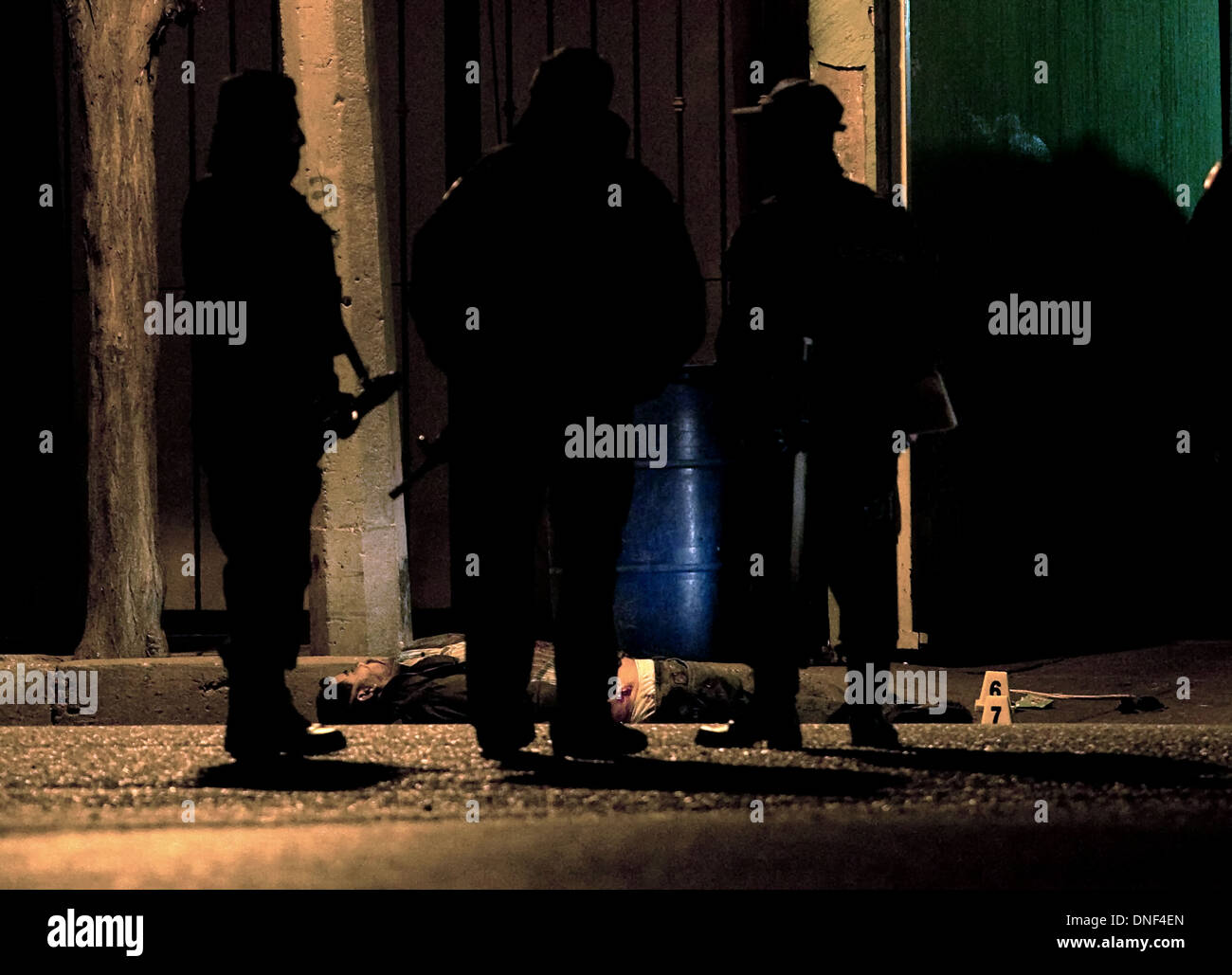 Un enquêteur de police examine le corps d'un homme tué par cartel qu'il a rendu visite à sa famille le 14 janvier 2009 à Juarez, au Mexique. Le tournage, liée à la drogue en cours à une guerre qui a déjà fait plus de 40 personnes depuis le début de l'année. Plus de 1600 personnes ont été tuées à Juarez en 2008, faisant de la ville la plus violente Juarez au Mexique. Banque D'Images