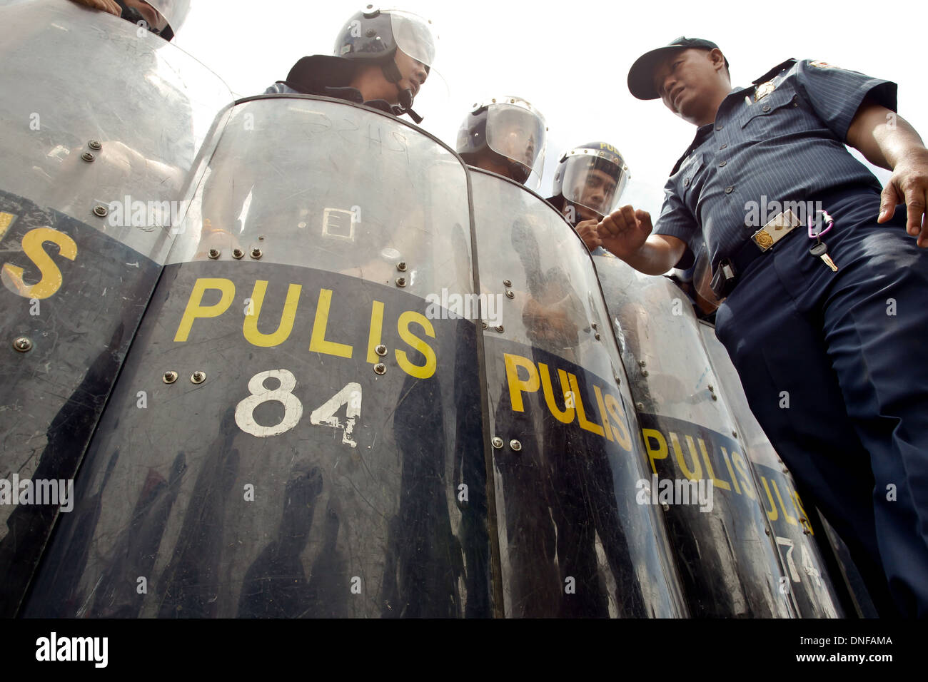 Un agent de police dans les contrôles sur la position de la police anti-émeute lors d'une manifestation devant le Président's SONA Banque D'Images