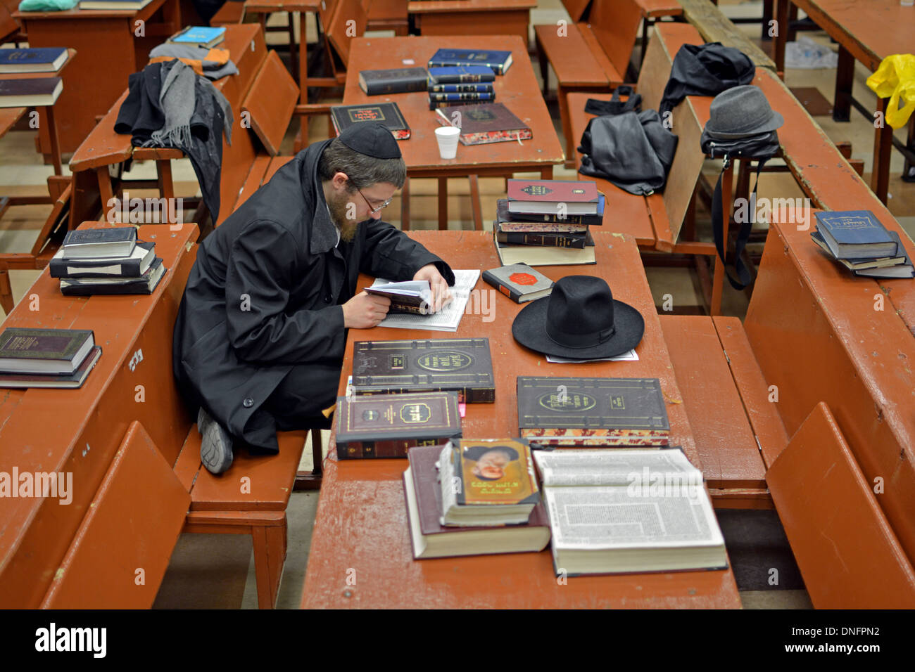 Un étudiant juif orthodoxe seul dans une grande pièce encombrée à Loubavitch siège à Crown Heights, Brooklyn, NY Banque D'Images