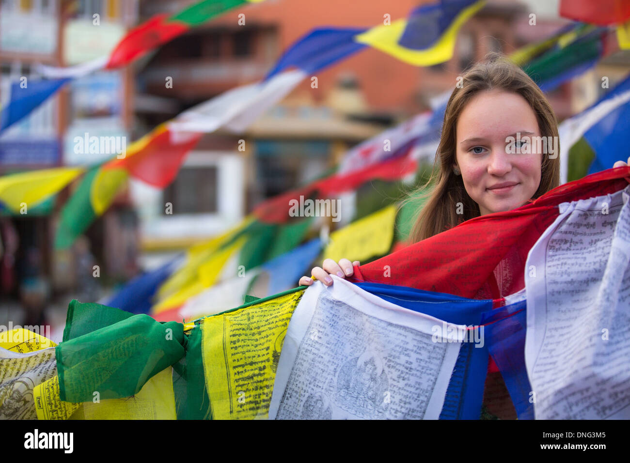 Teen girl à monastère bouddhiste, avec des drapeaux de prières bouddhistes voler. Banque D'Images