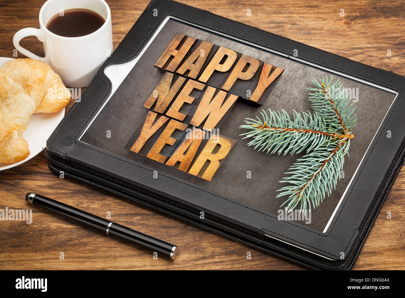 Bonne année dans la typographie type bois sur un ordinateur tablette numérique avec stylet, tasse de café et pâtisserie Banque D'Images