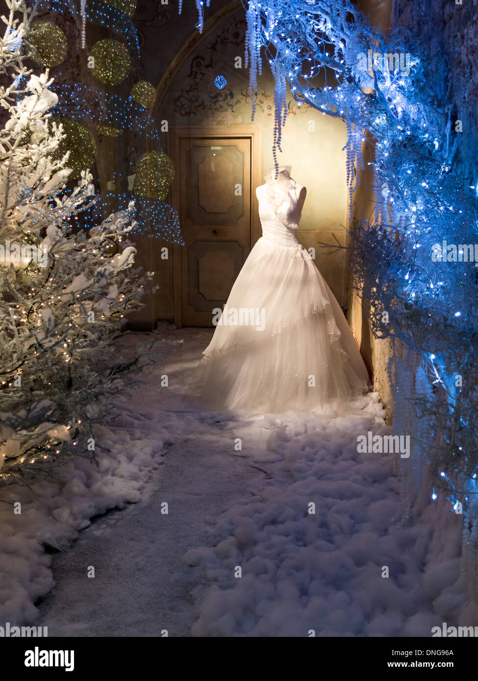 Habillage de fenêtres d'hiver d'un magasin de détail avec feux bleus et neige avec une élégante robe sur un mannequin Banque D'Images