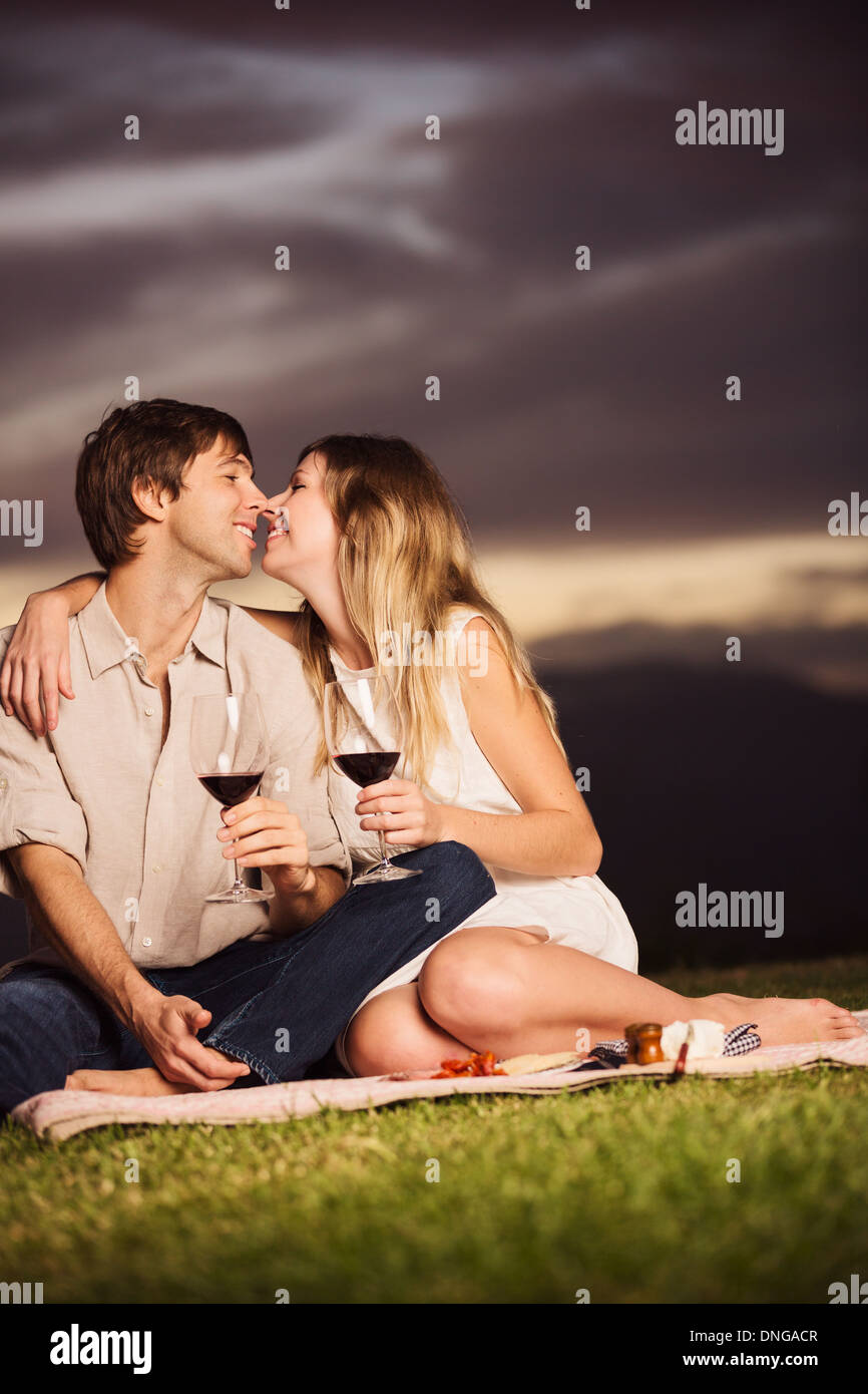 Beau couple de boire dans un verre de vin sur pique-nique romantique au coucher du soleil Banque D'Images